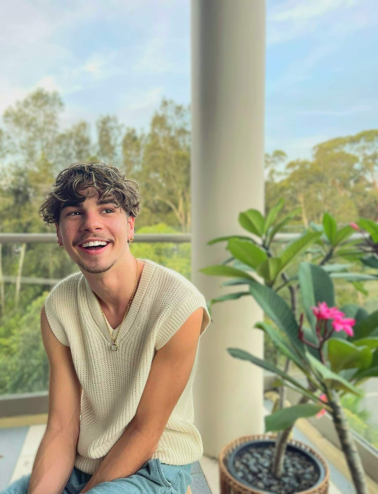 a man sitting on a balcony with a plant in front of him