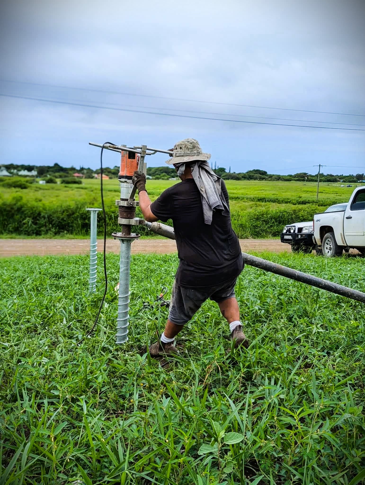 Ouvrier installant un pieu vissé en acier galvanisé sur terrain meuble
