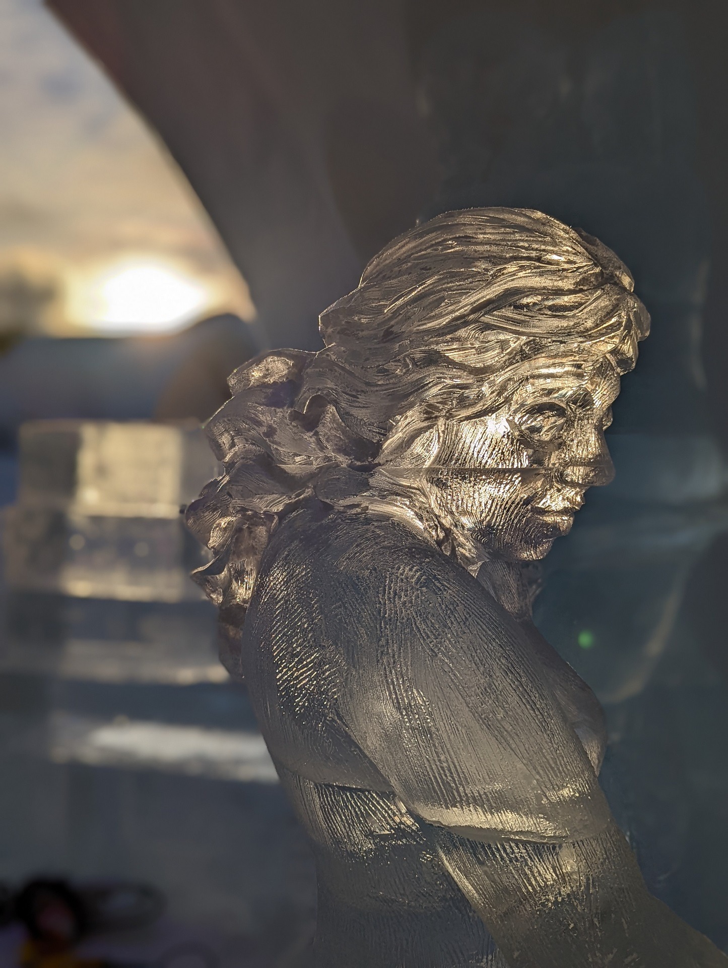ice sculpture of a delicate feminine figure with dramatic late day lighting