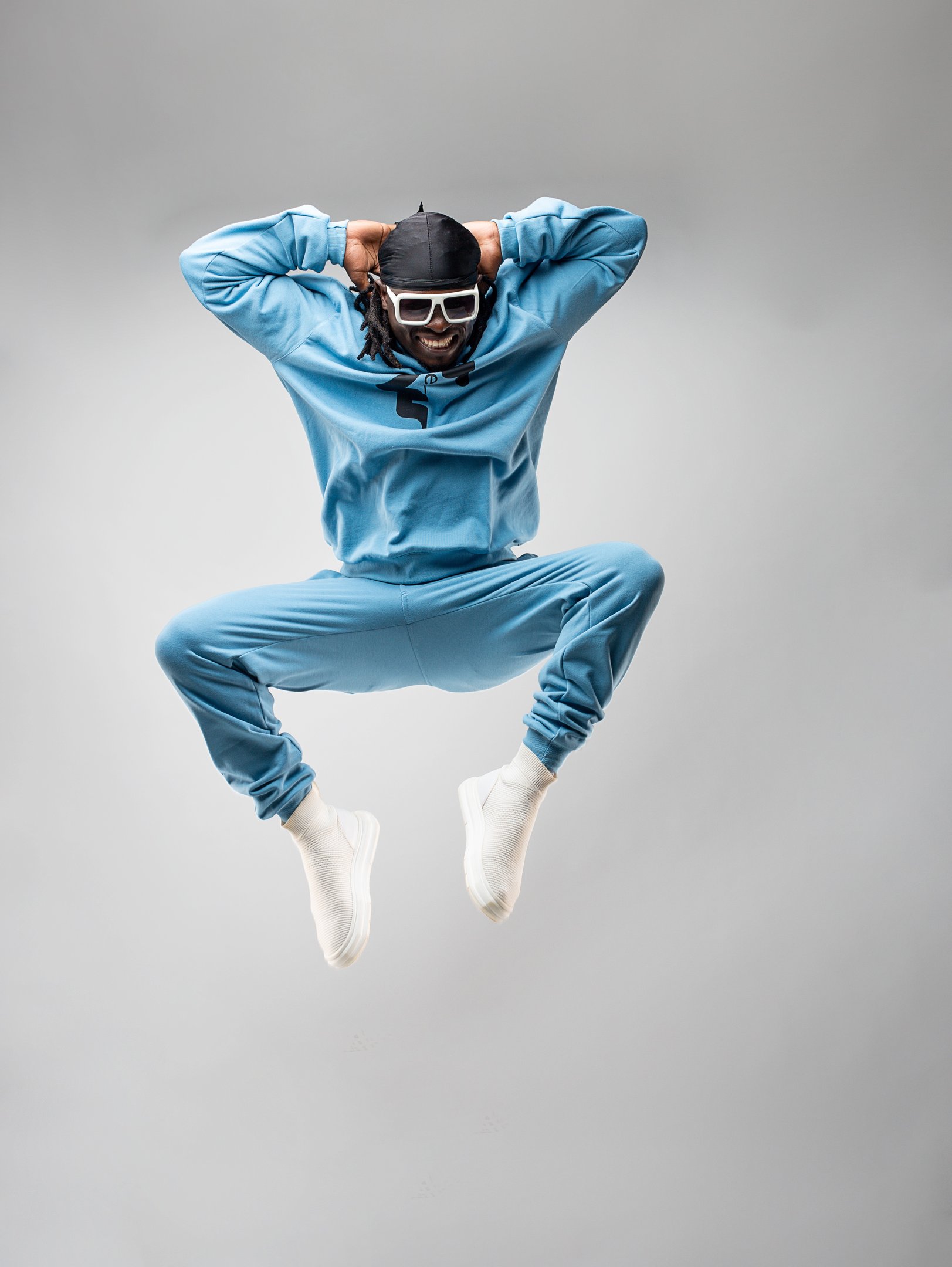Dancer Chiluba TheOne, founder of TheOne Studios jumping in a blue sweat shirt and pants