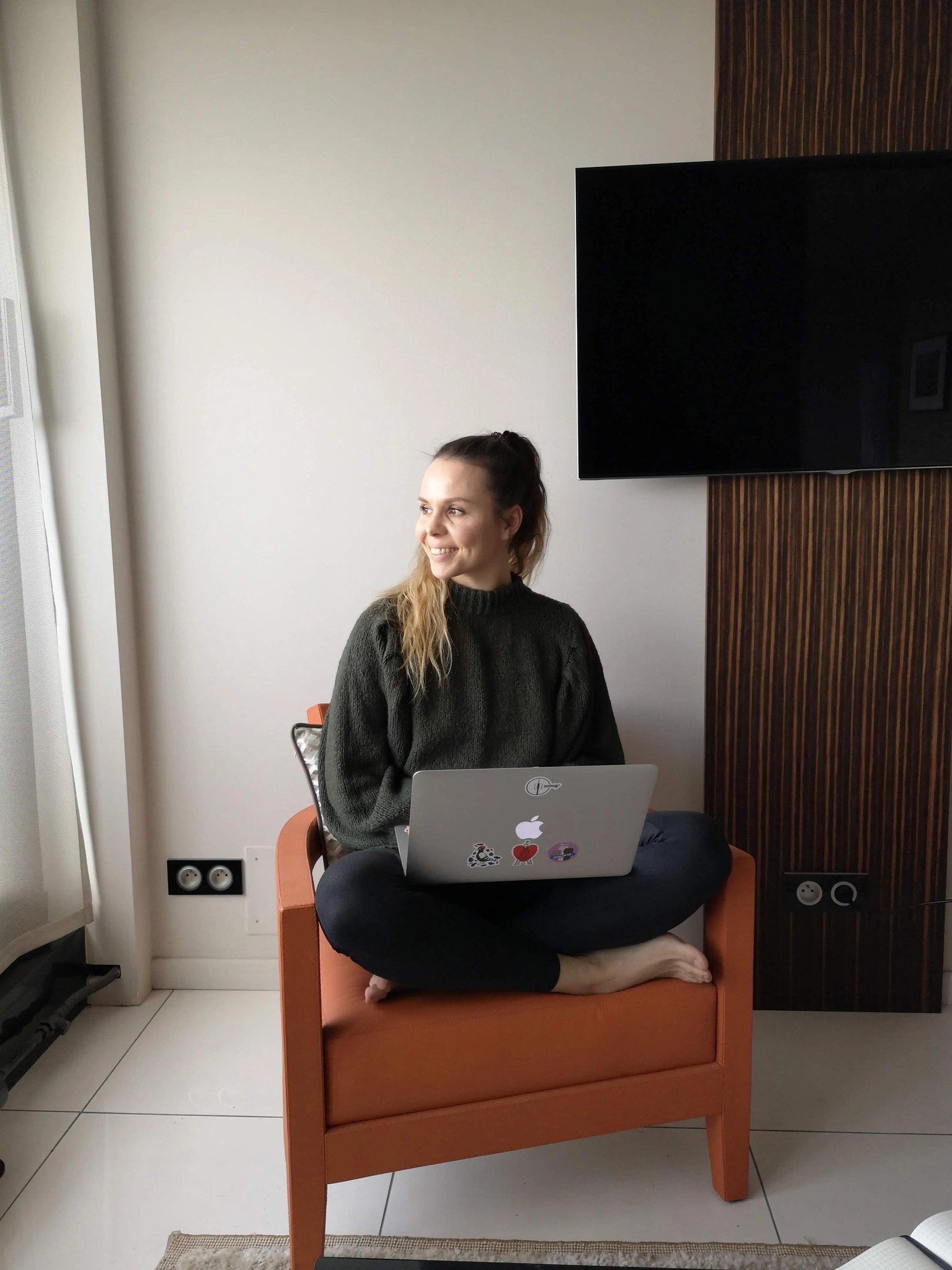Christine Hauser, RTT Practitioner, sitting on a chair with laptop, smiling, looking into distance