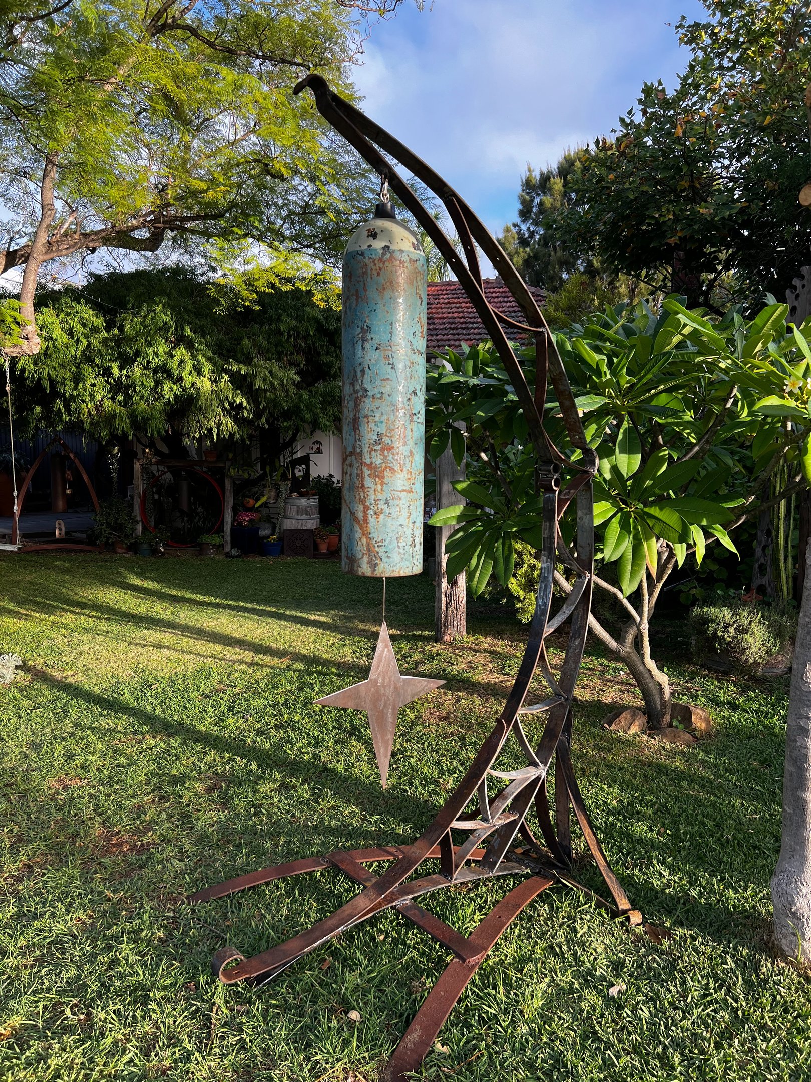 tall garden sculpture with large gong in shape of moon and star