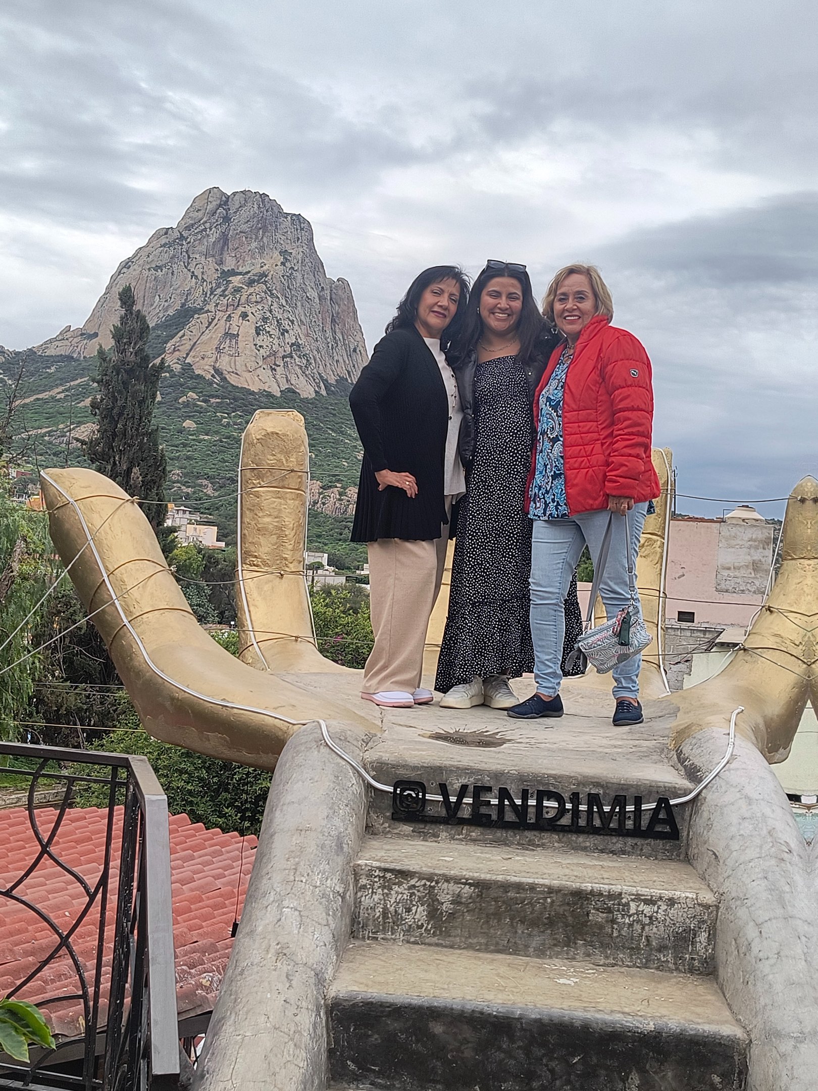 Familia en una mano gigante y al fondo la peña de bernal
