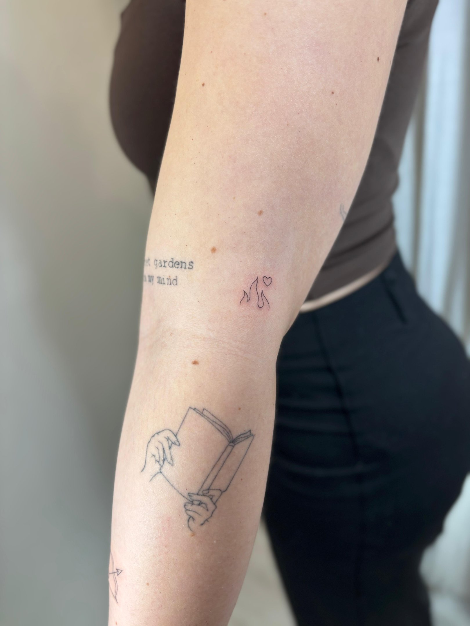 Tatuaje fineline en Madrid de frase gardens in my mind con figura abstracta de gatos y corazón en el