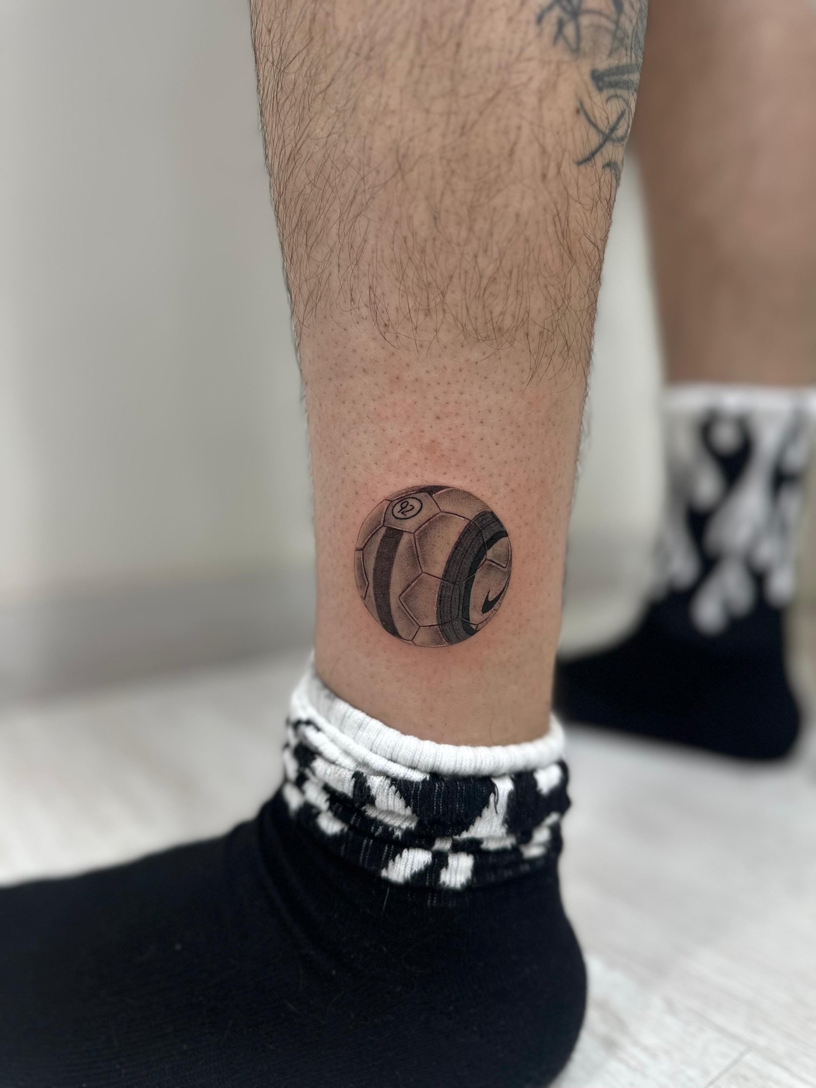 Tatuaje microrealismo en Madrid de balón de fútbol Nike con sombreado fotorrealista en la pierna