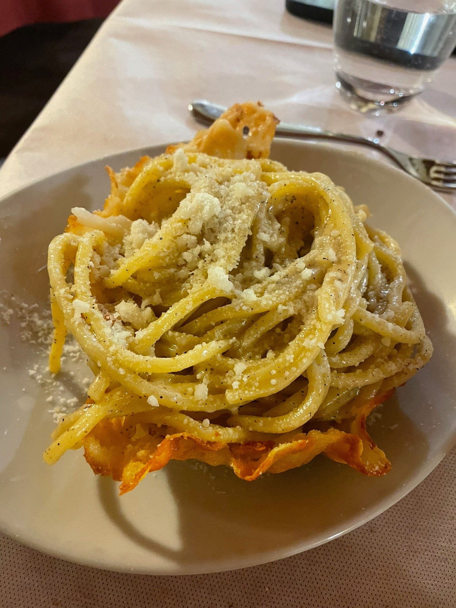 Authentic Italian Cacio e Pepe pasta served in a crispy Parmesan cheese bowl with cracked black pepper.