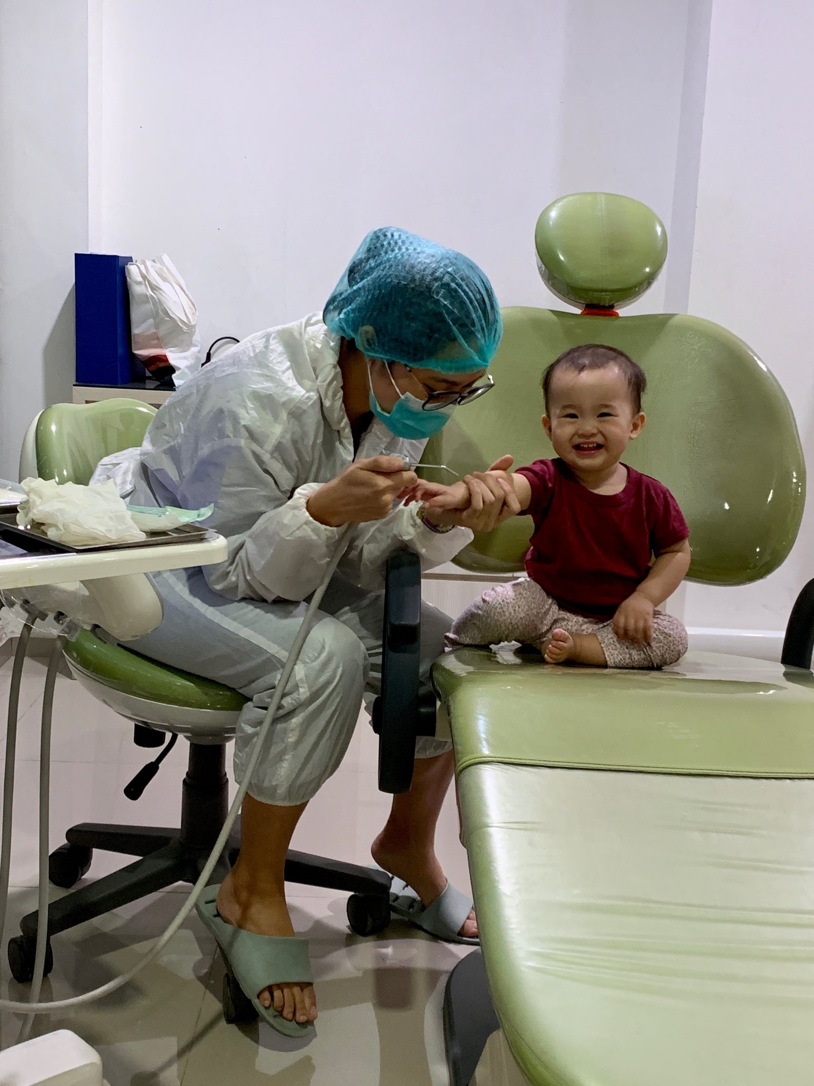 a woman in a surgical mask and a baby in a chair