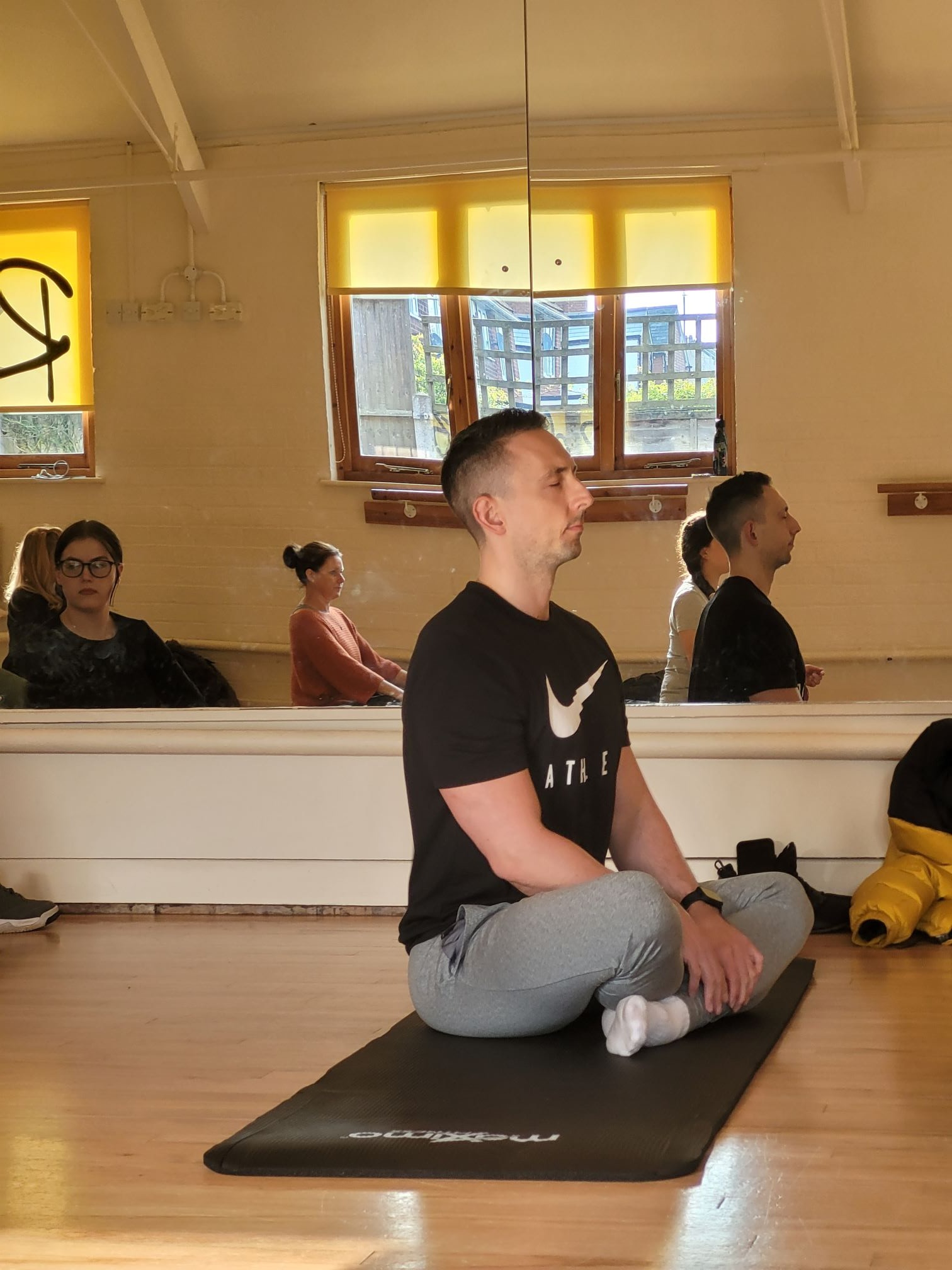 A man sat up straight meditating in a yoga class