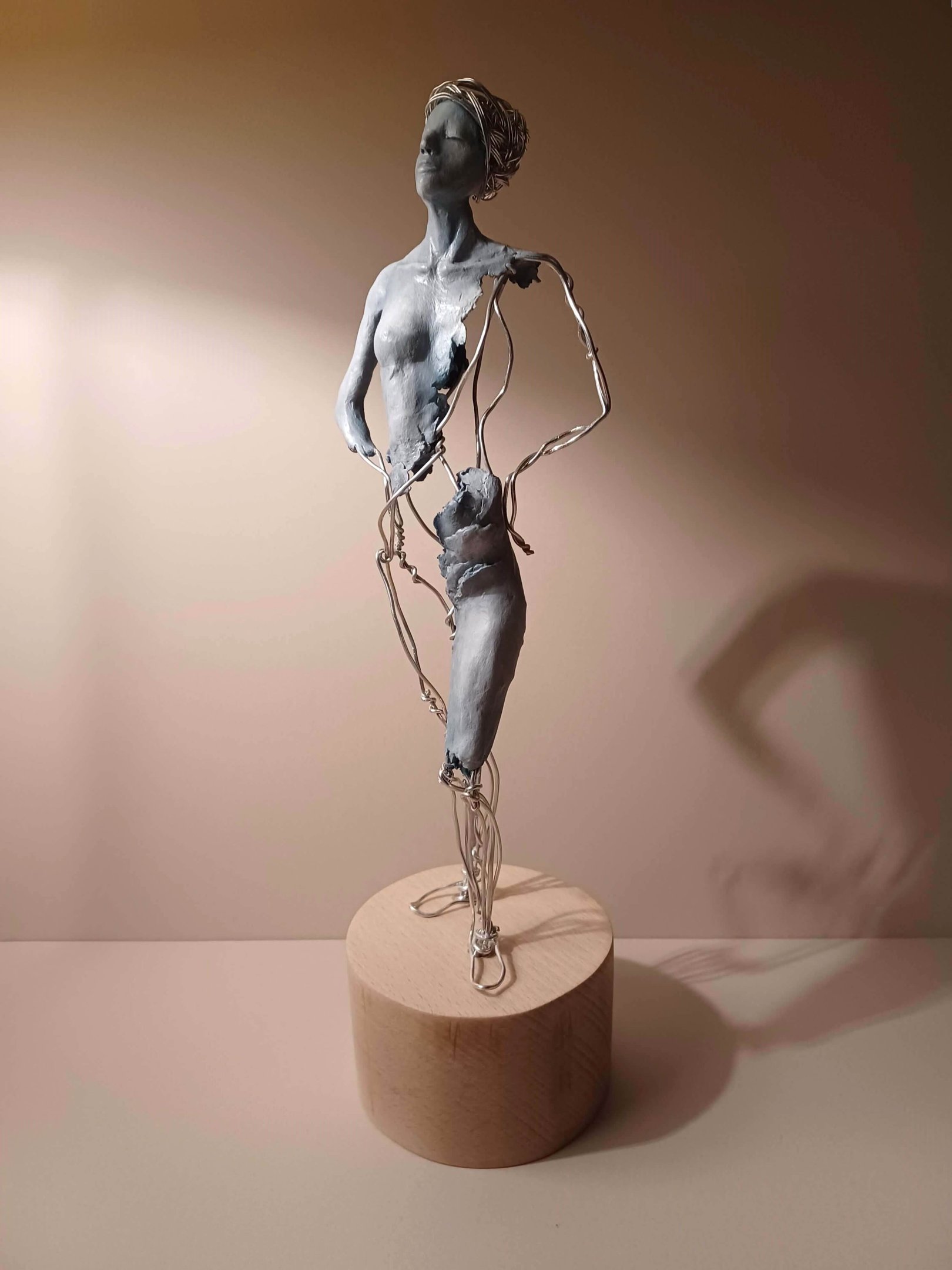 A complete sculpture of a standing female figure, part clay, part wire, hands on hips