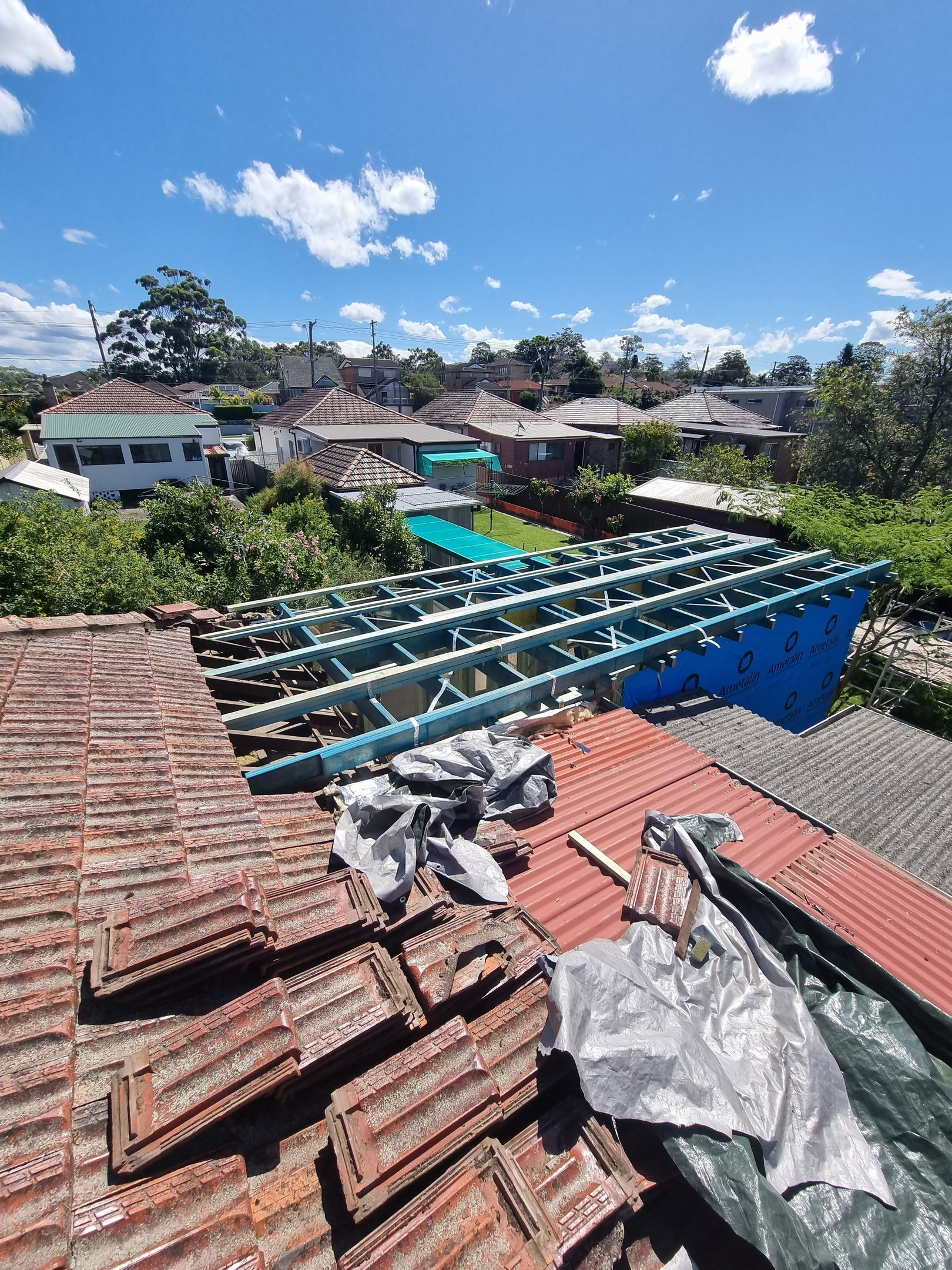 Residential roof extension under construction showing timber framing and terracotta tiles.
