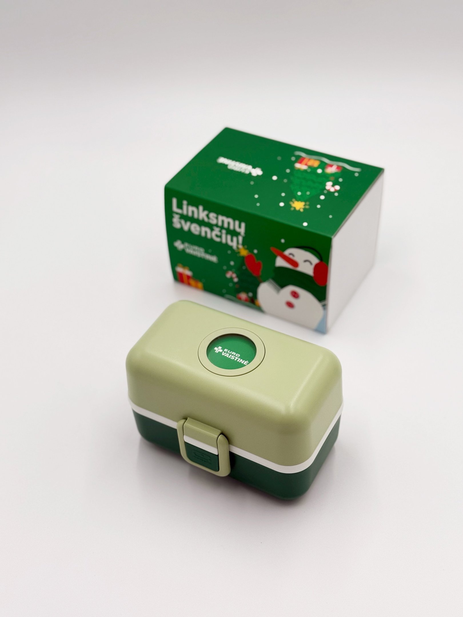 Green and light green Eurovaistine lunch box with a snowman-themed holiday gift box.