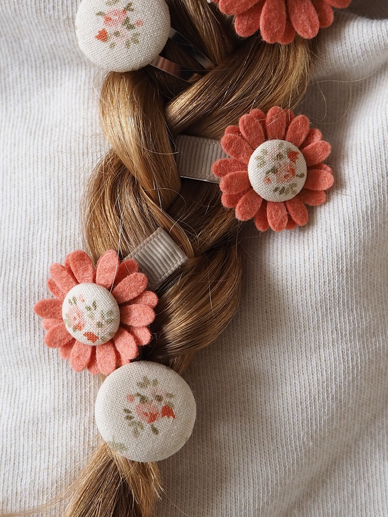 warkocz z włosów ozdobionymi spinkami do włosów w kwiaty