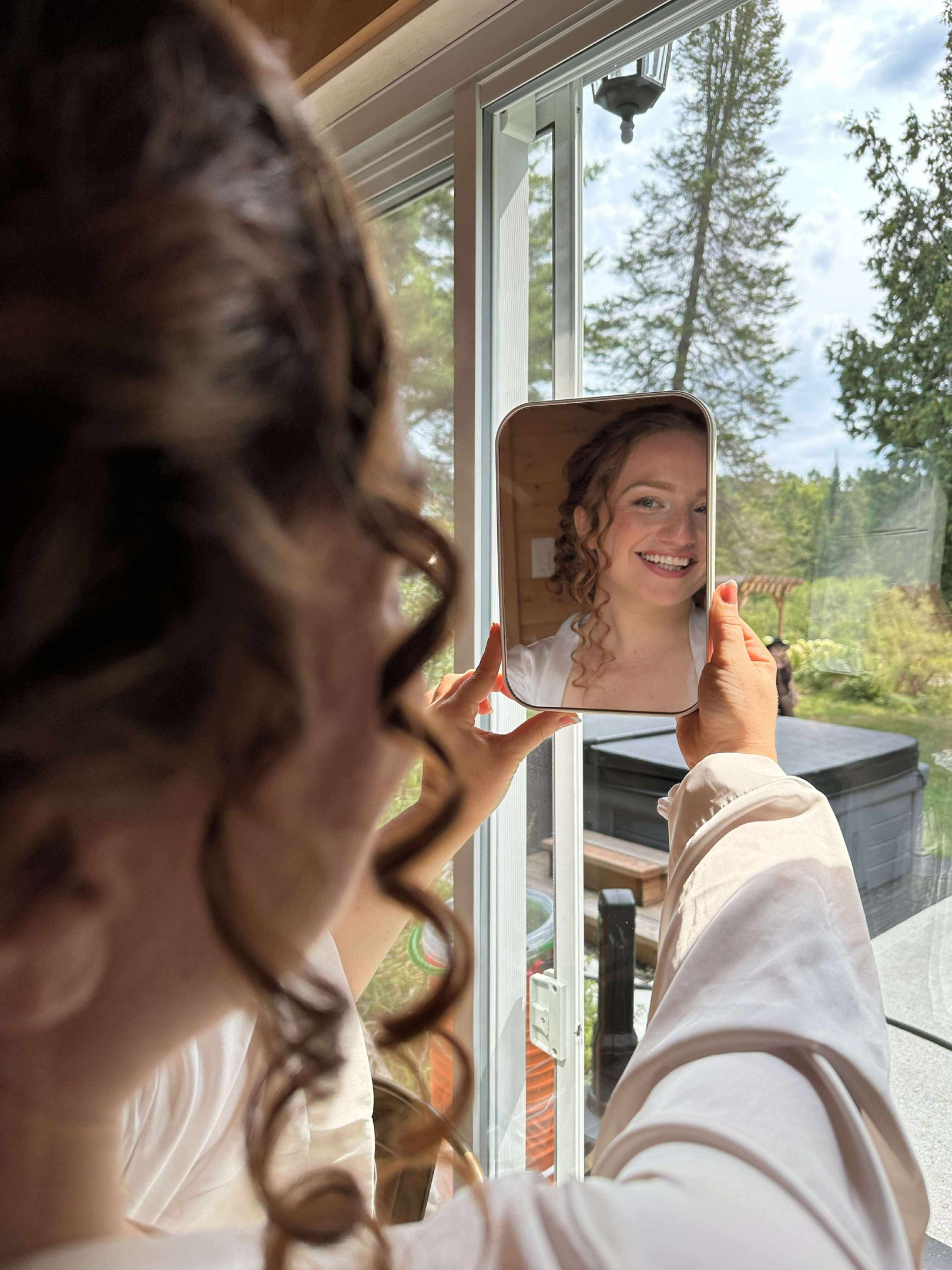une mariée se regarde dans le miroir après son maquillage et sa coiffure et elle est heureuse