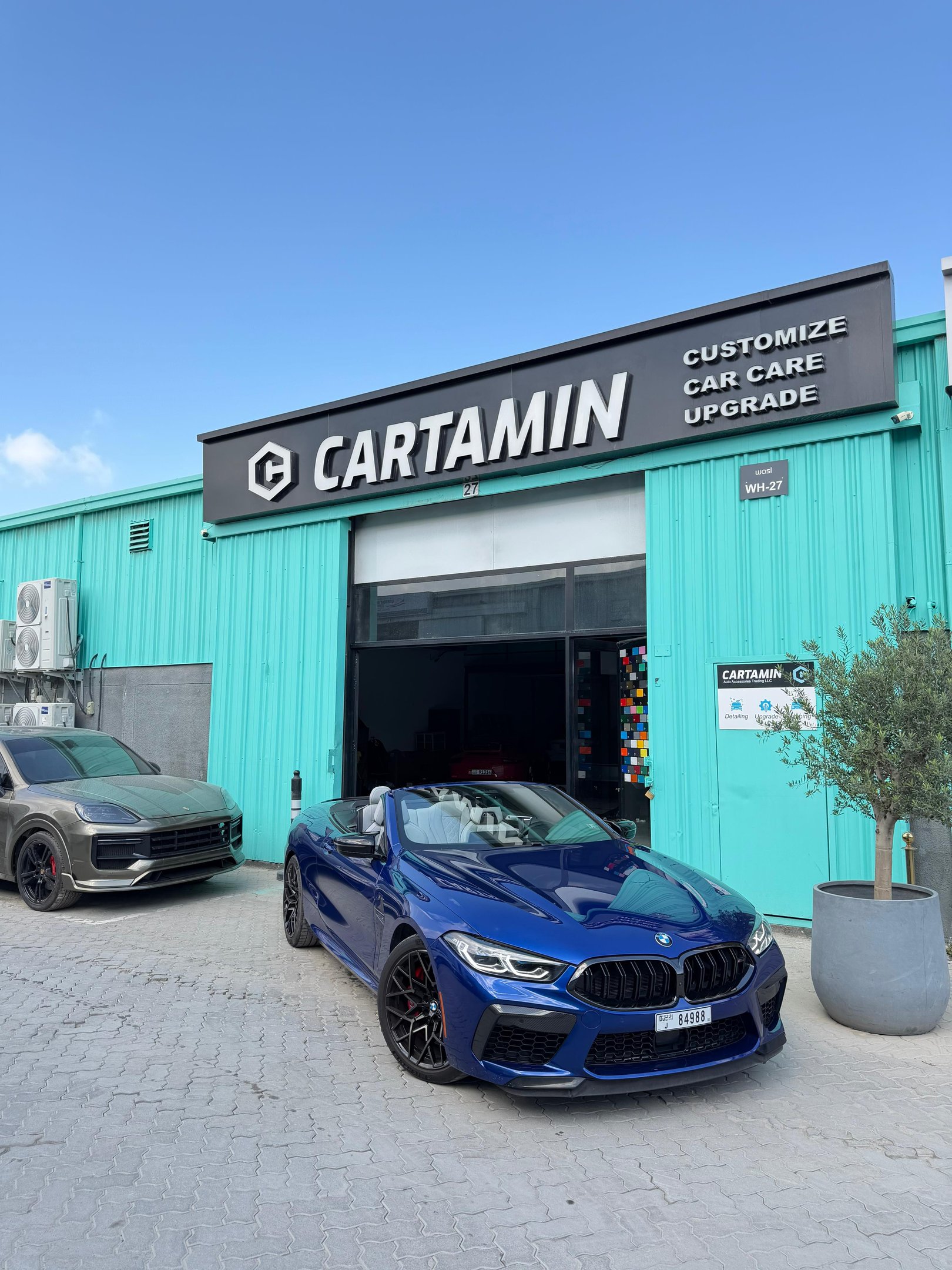 A blue BMW M8 convertible parked outside Cartamin car care workshop for professional detailing and upgrades.