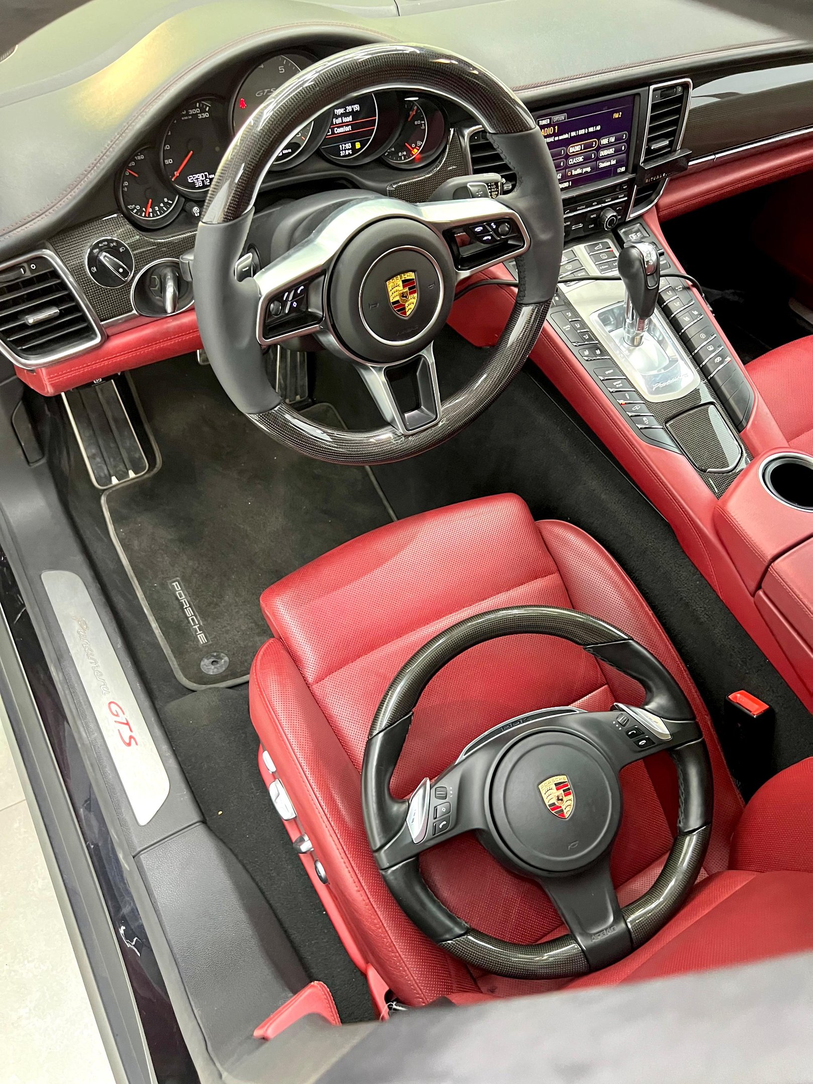 Luxury Porsche GTS interior featuring red leather seats and a carbon fiber steering wheel.