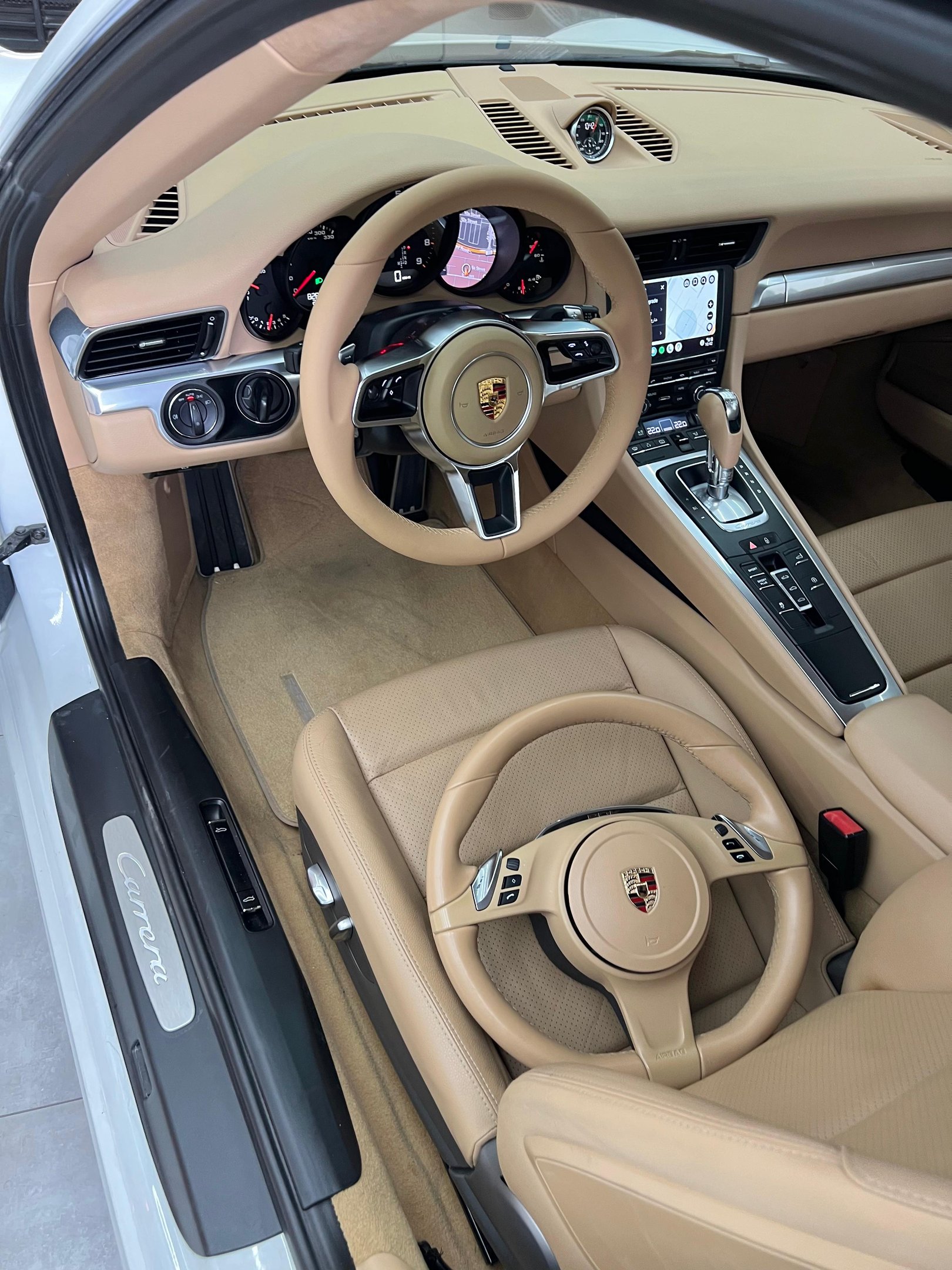 Luxurious tan leather Porsche Carrera interior featuring two matching steering wheels and dashboard.
