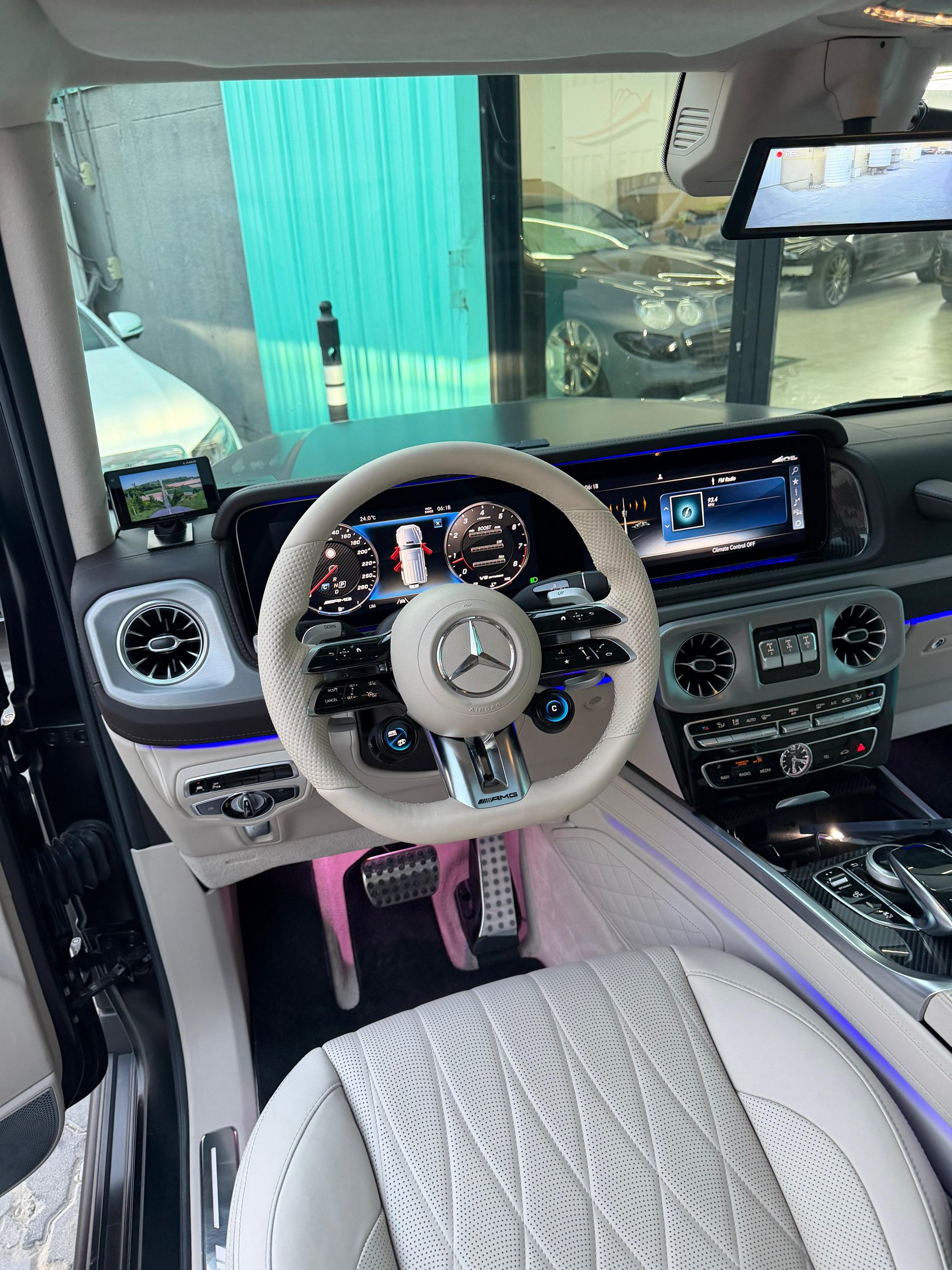 Luxurious Mercedes-Benz AMG G-Wagon interior featuring a white leather steering wheel and digital dashboard.