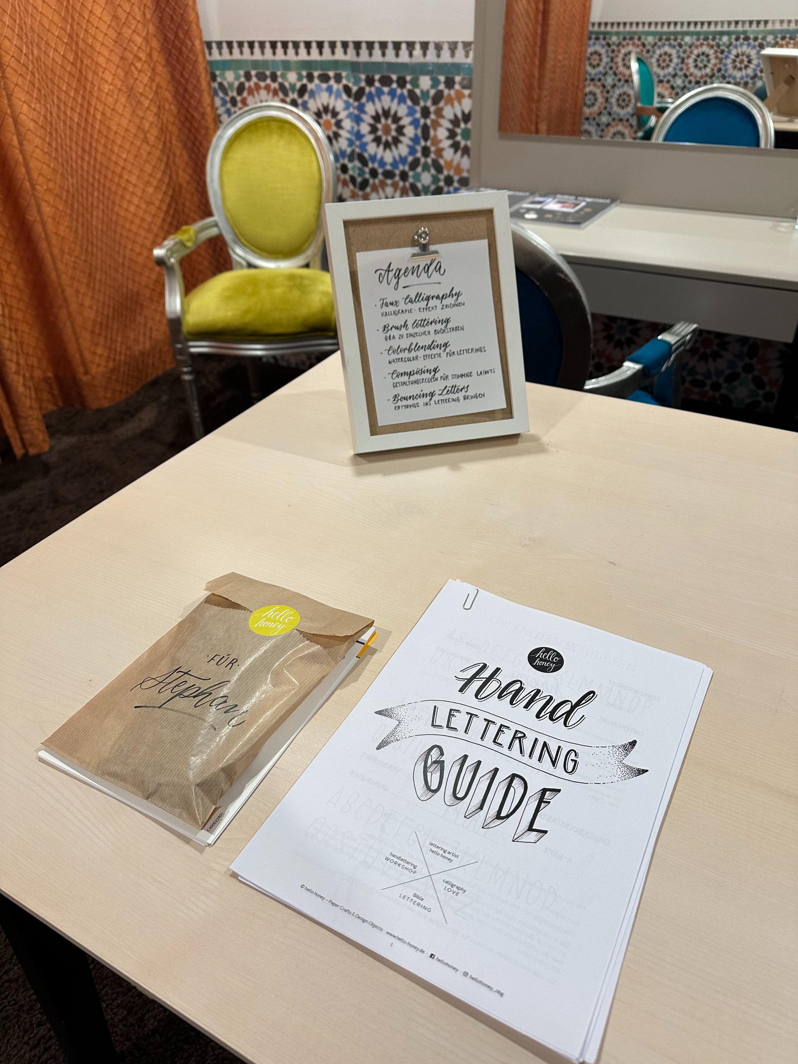 Hand lettering guide and workshop agenda on a desk for a creative calligraphy class.