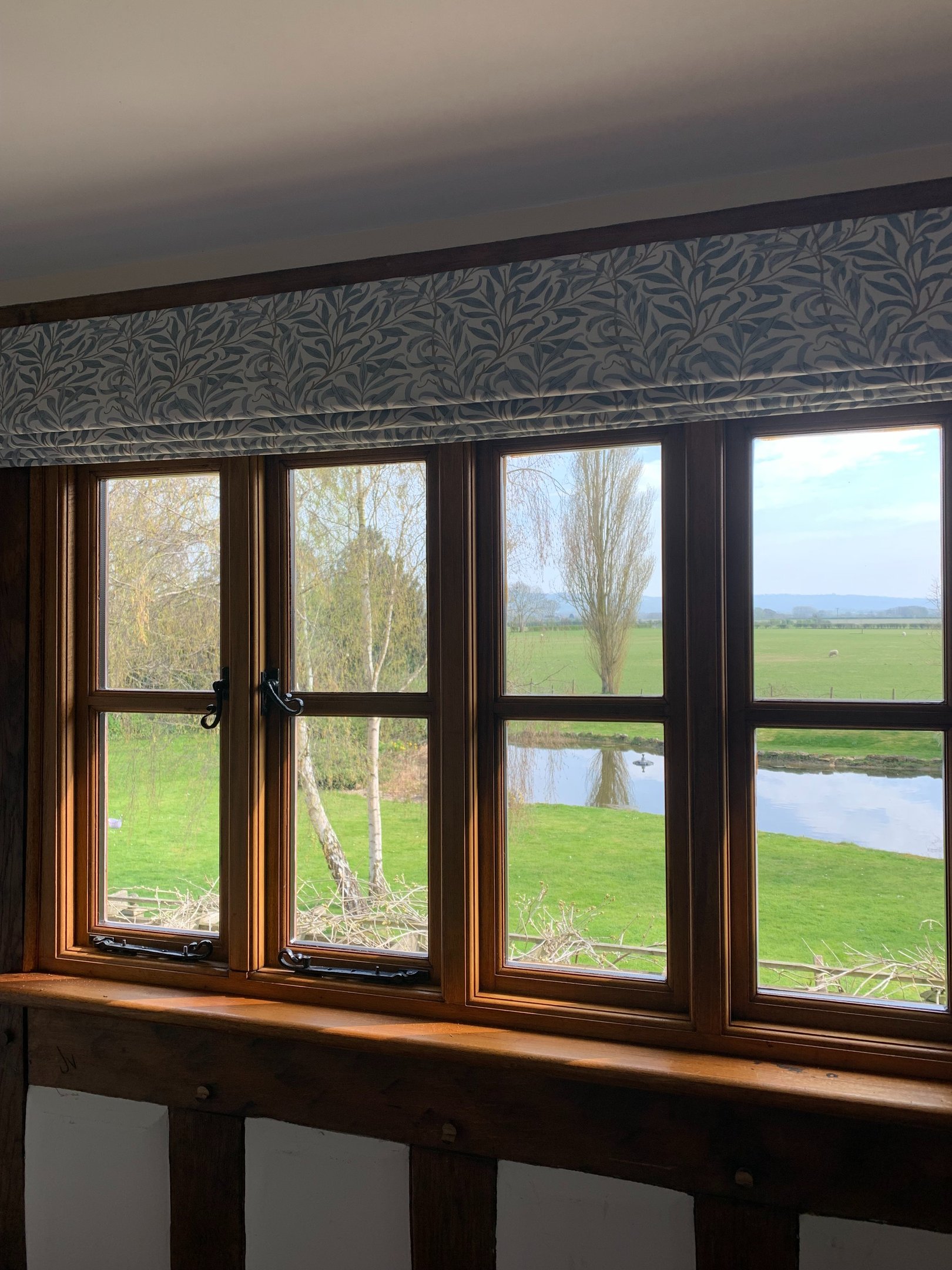 A roman blind in a leafy fabric designed to work with the view of open fields