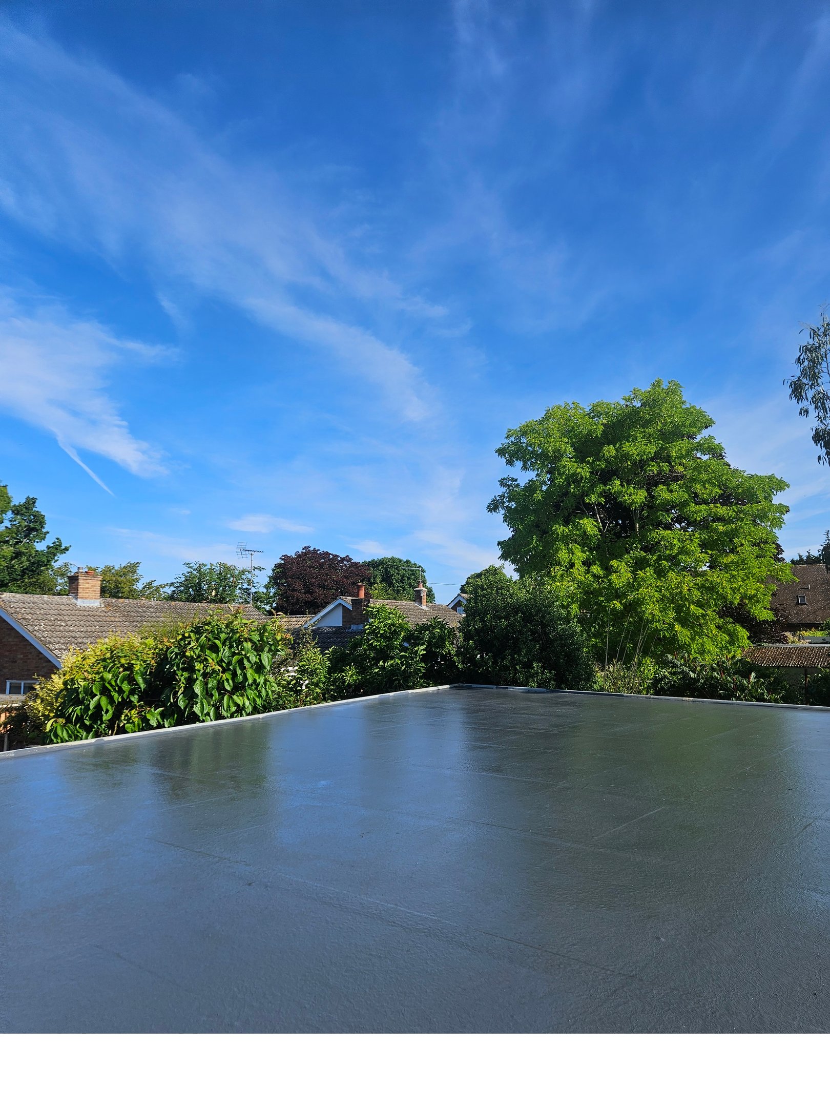 Modern grey flat roof installation with a smooth waterproof finish under a blue sky.