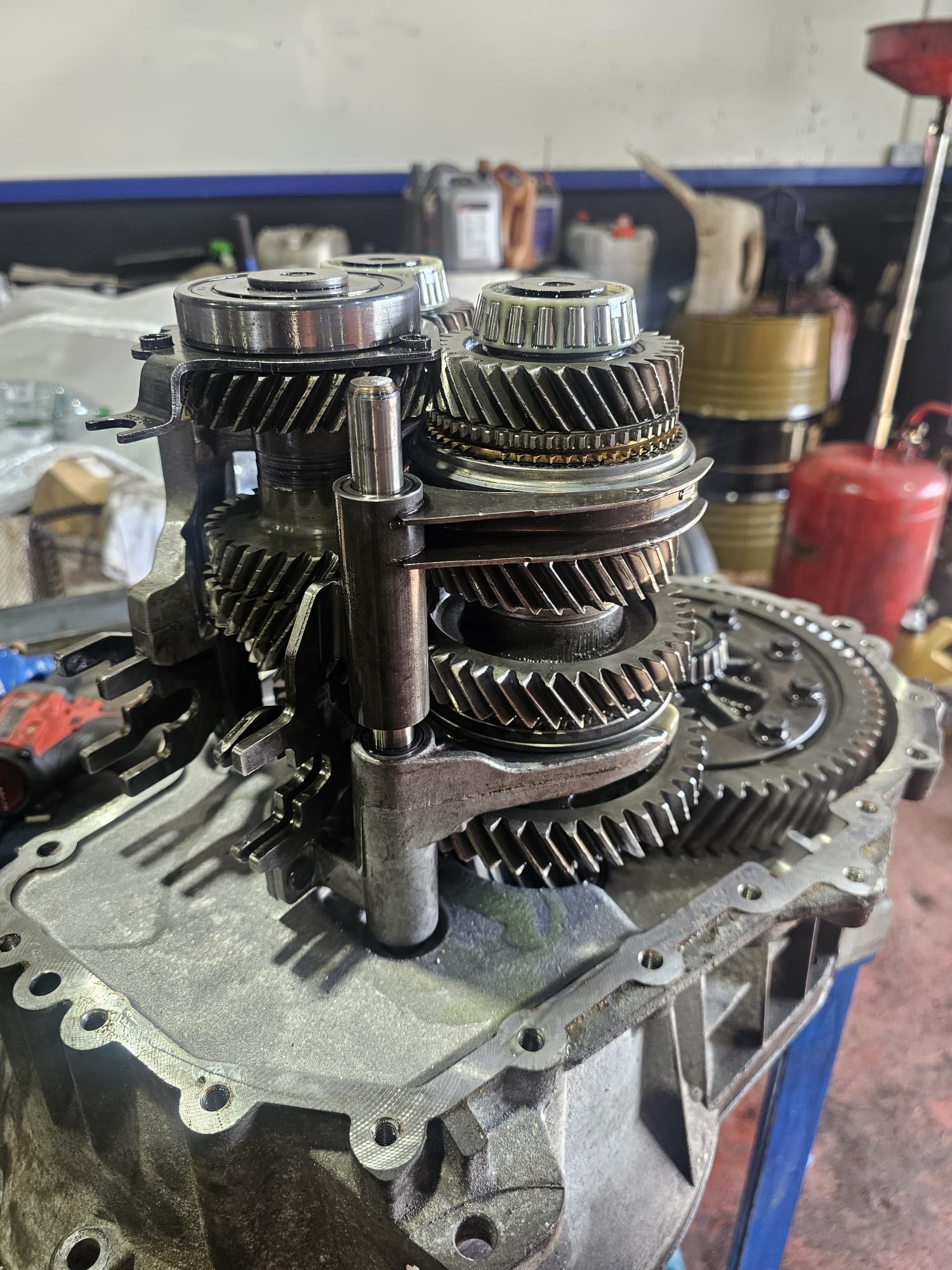 Manual car transmission gears and internals being repaired in an automotive workshop.