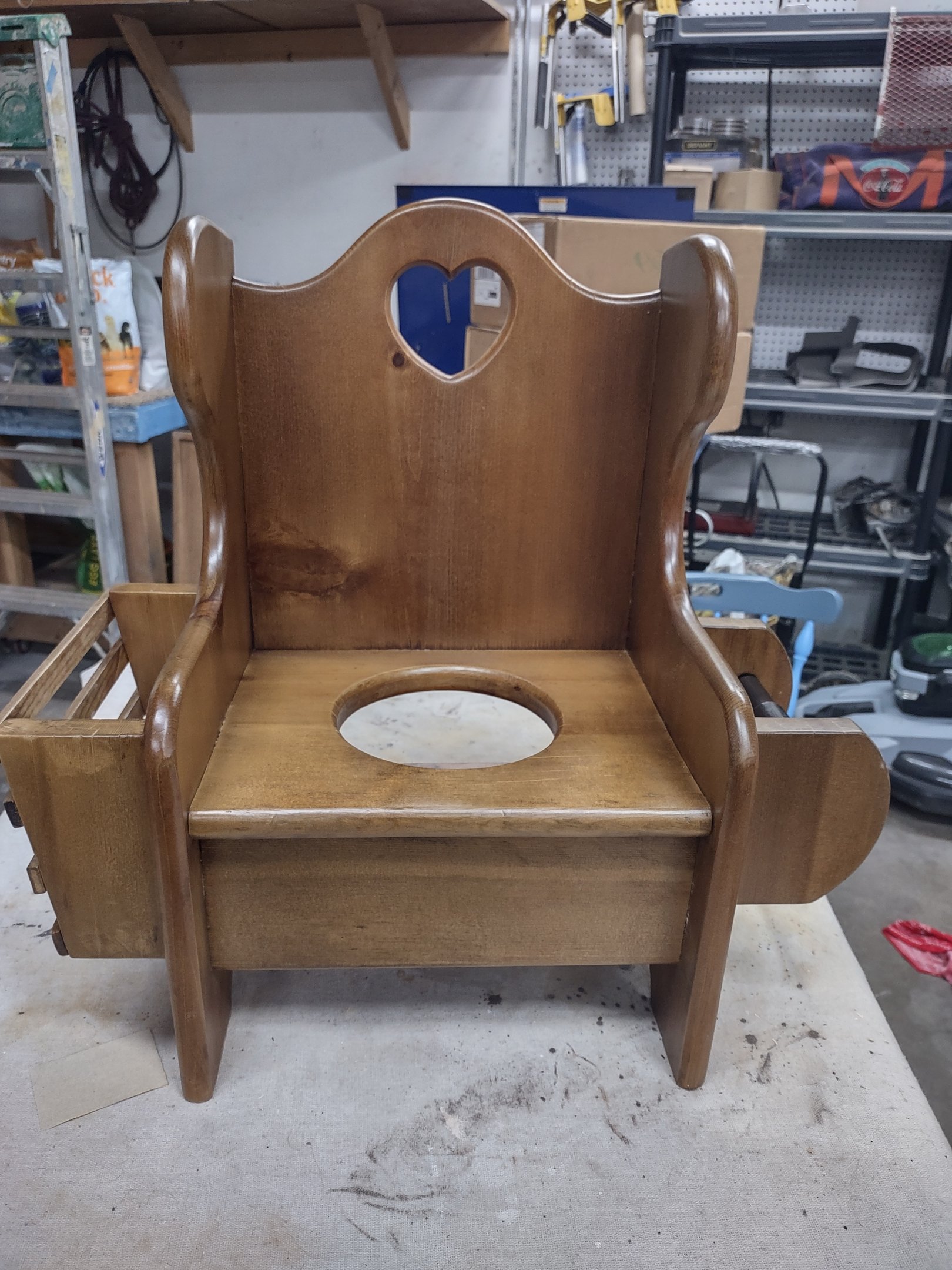  Restored antique wooden potty chair for toddlers featuring a heart cutout and side storage.