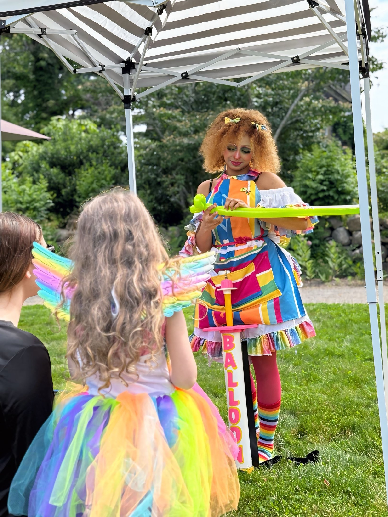 Balloon twister dressed in rainbow making a new shape