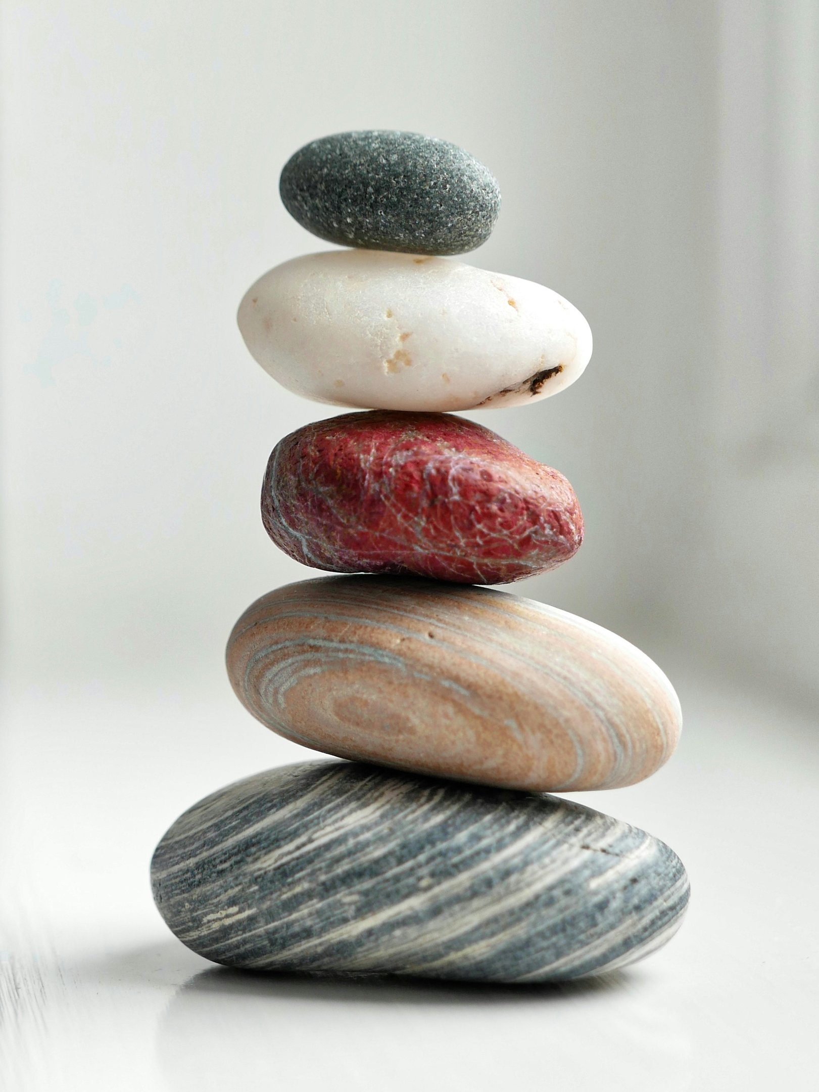 A balanced stack of five smooth river stones in various colors representing zen and stability.