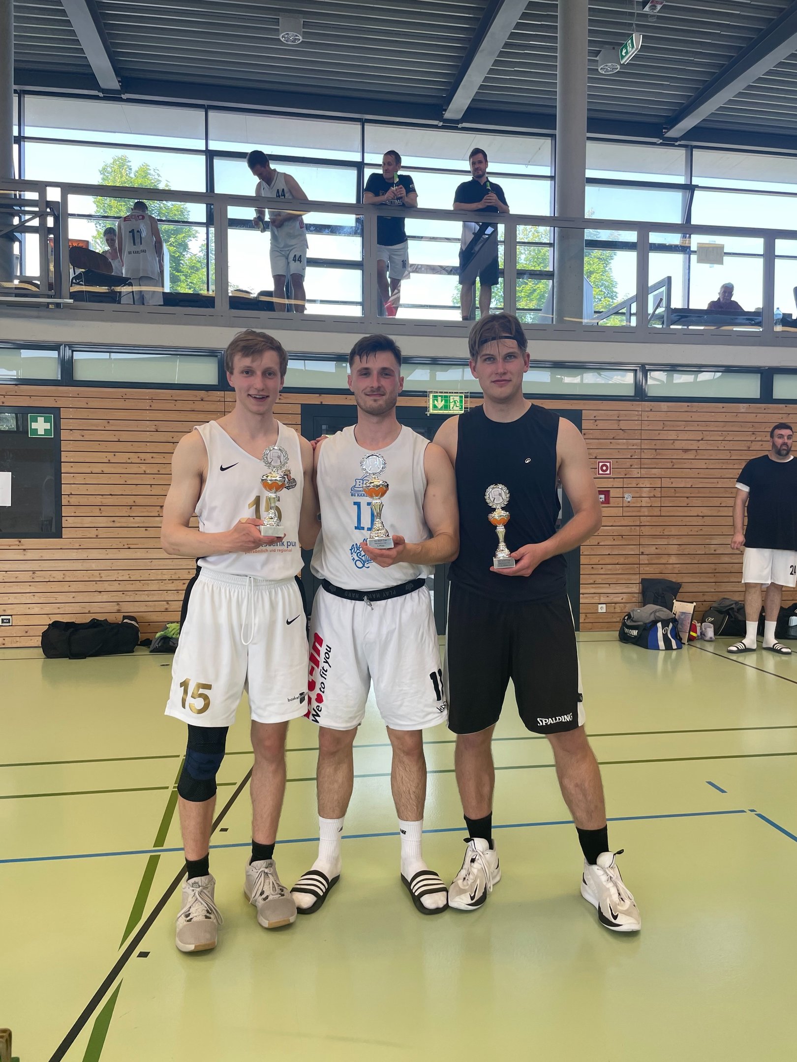 alt="Three basketball players displaying their individual trophies."