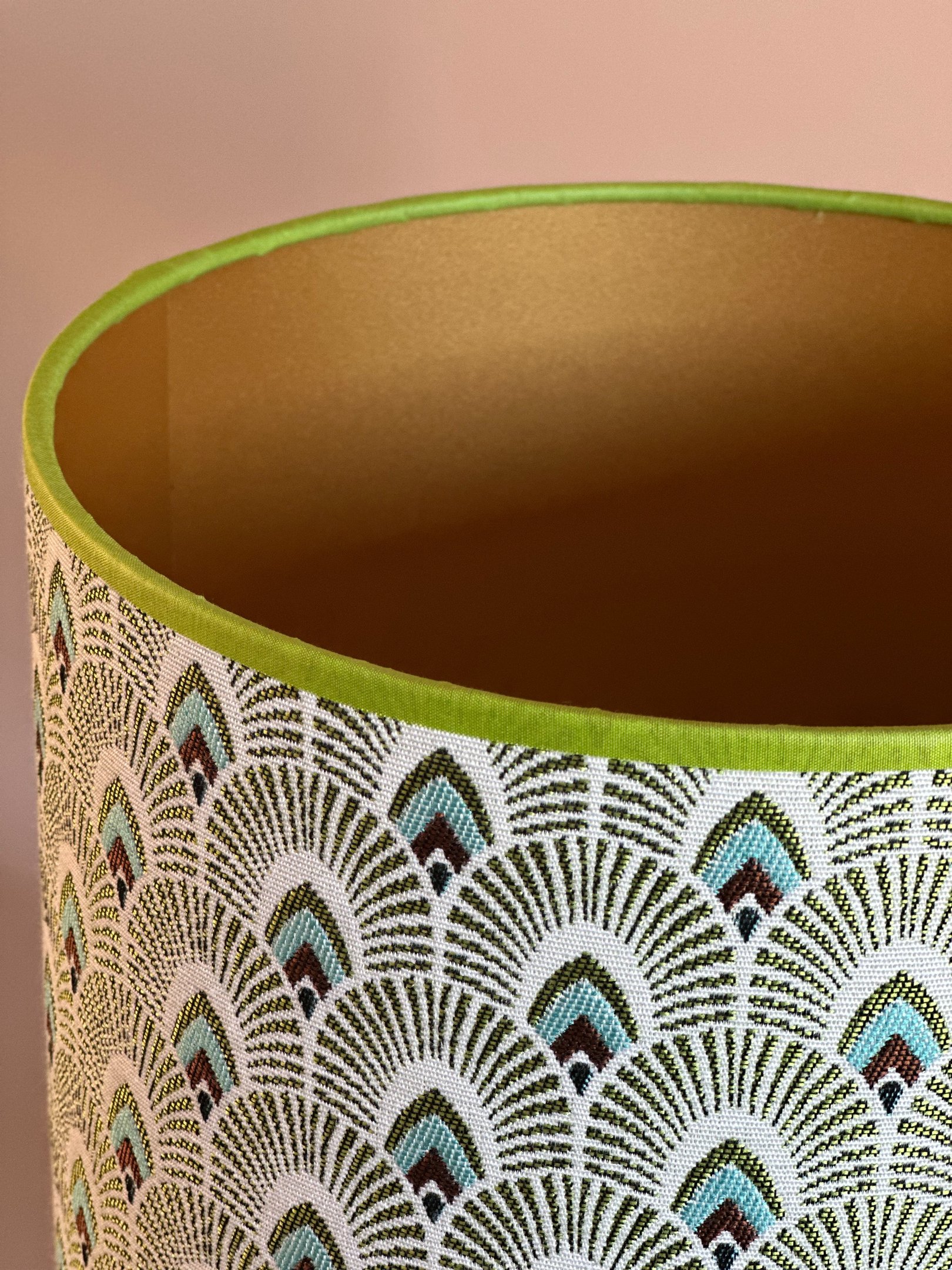 Green and gold art deco lampshade with fan pattern jacquard fabric and green trim.