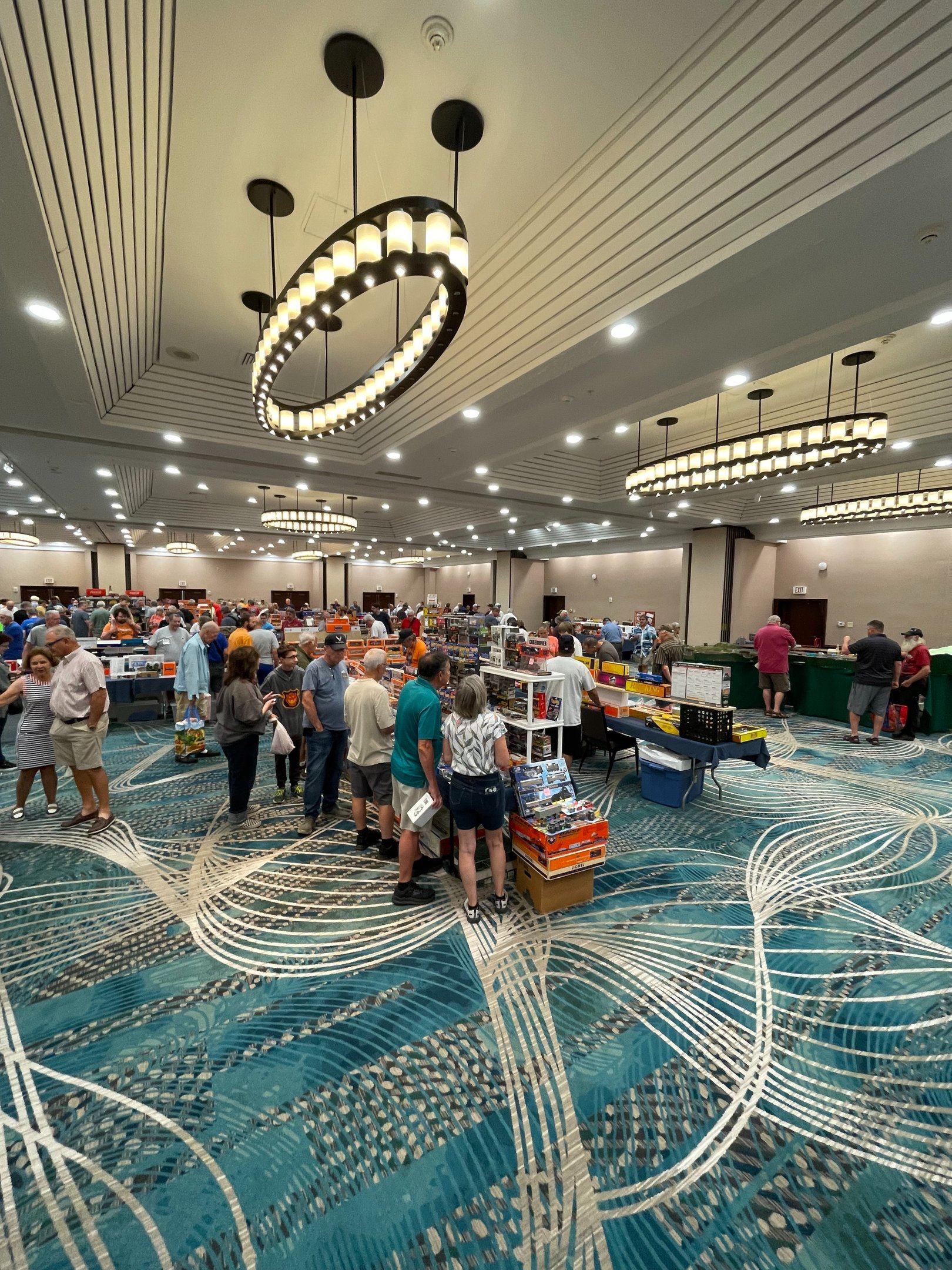 Collectors browsing model trains and layouts at a busy East Coast model train show.