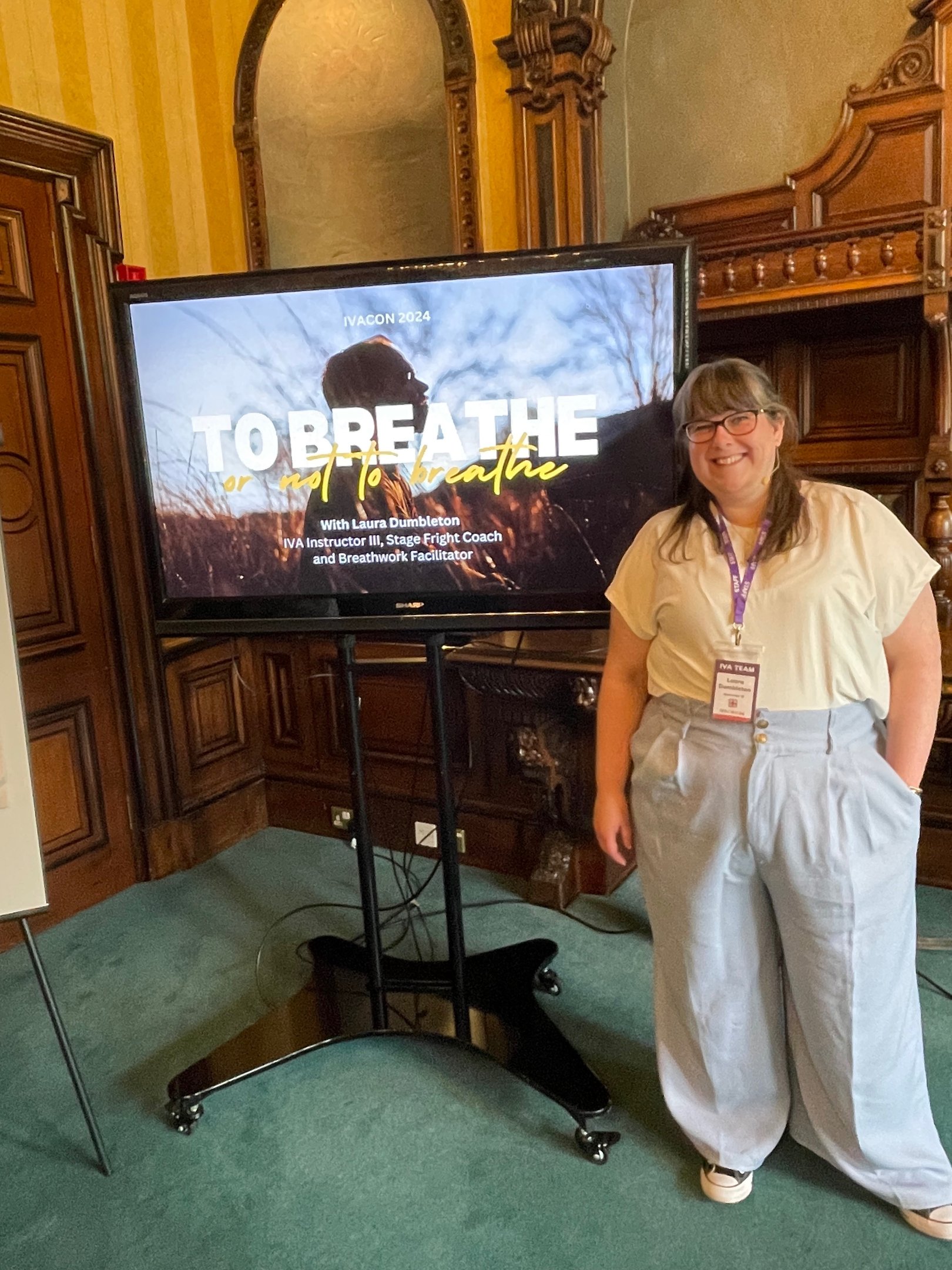 Laura is smiling towards the camera standing in front of her presentation on breathwork
