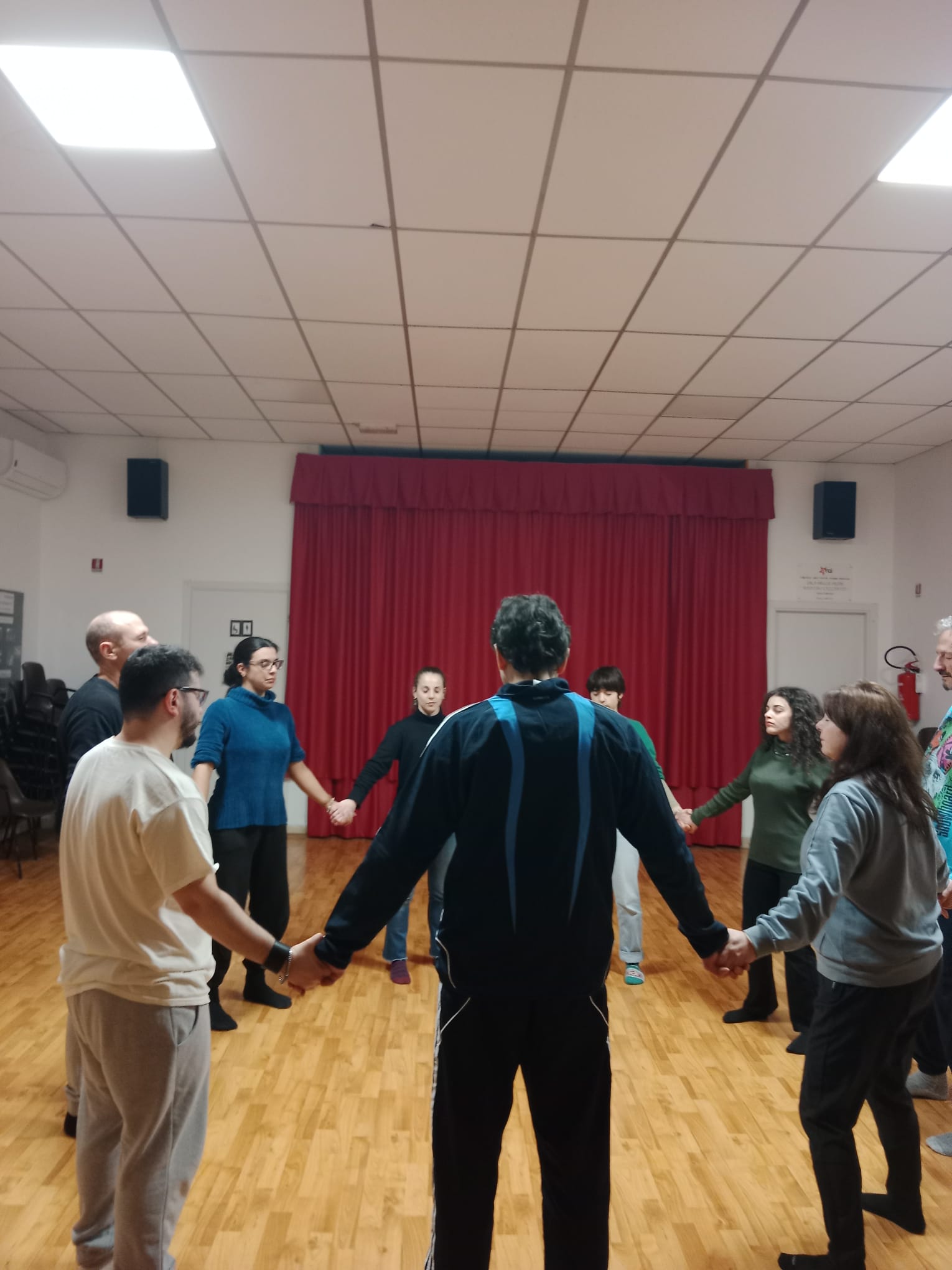 a group of people holding hands in a circle, classe di esercizi di bioenergetica