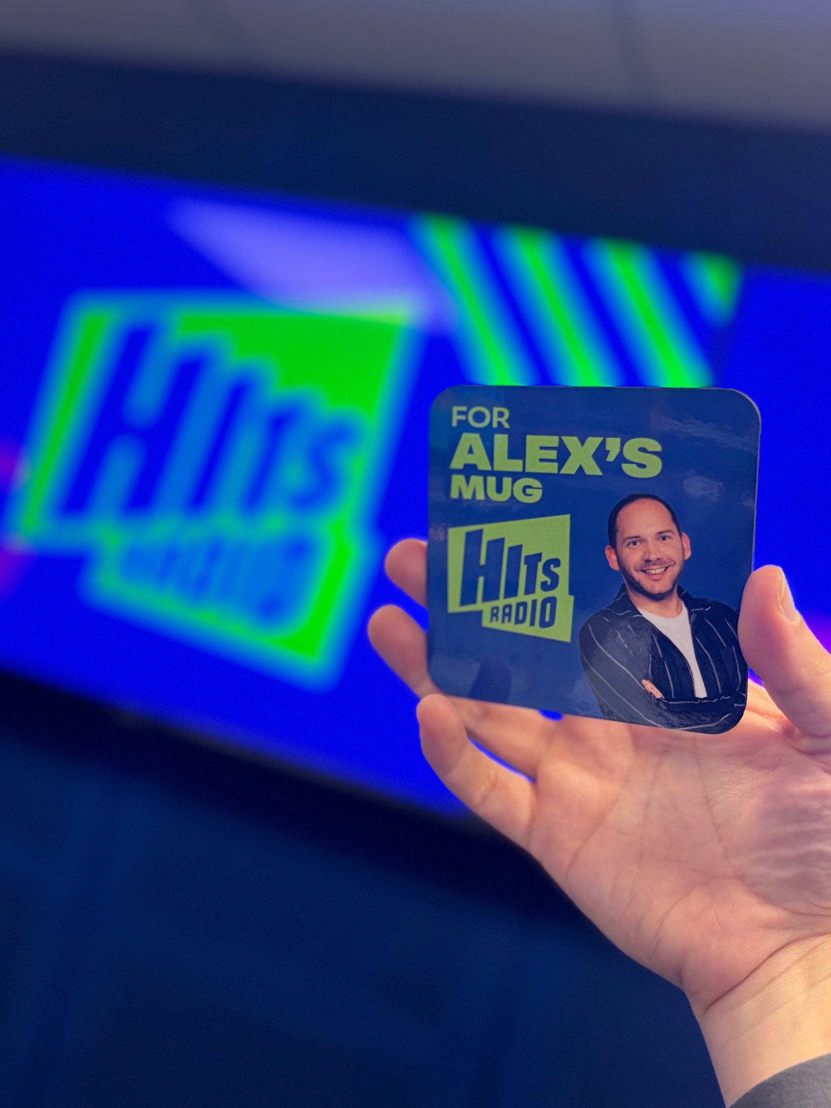 A Hits Radio drinks coaster that says 'for Alex's mug' on it.