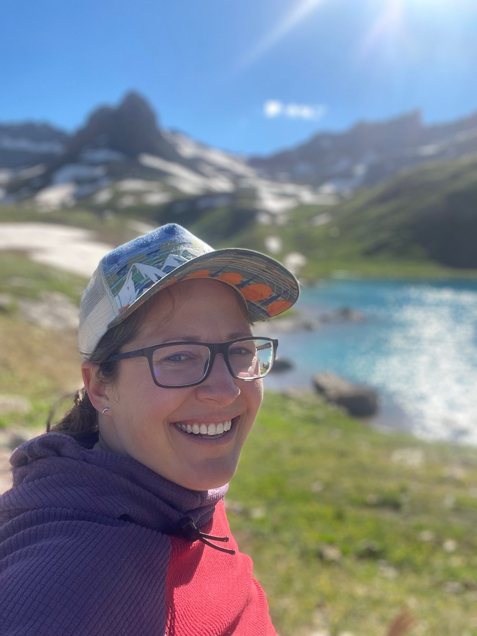 Jenna Smiling Outside in a hat by a lake