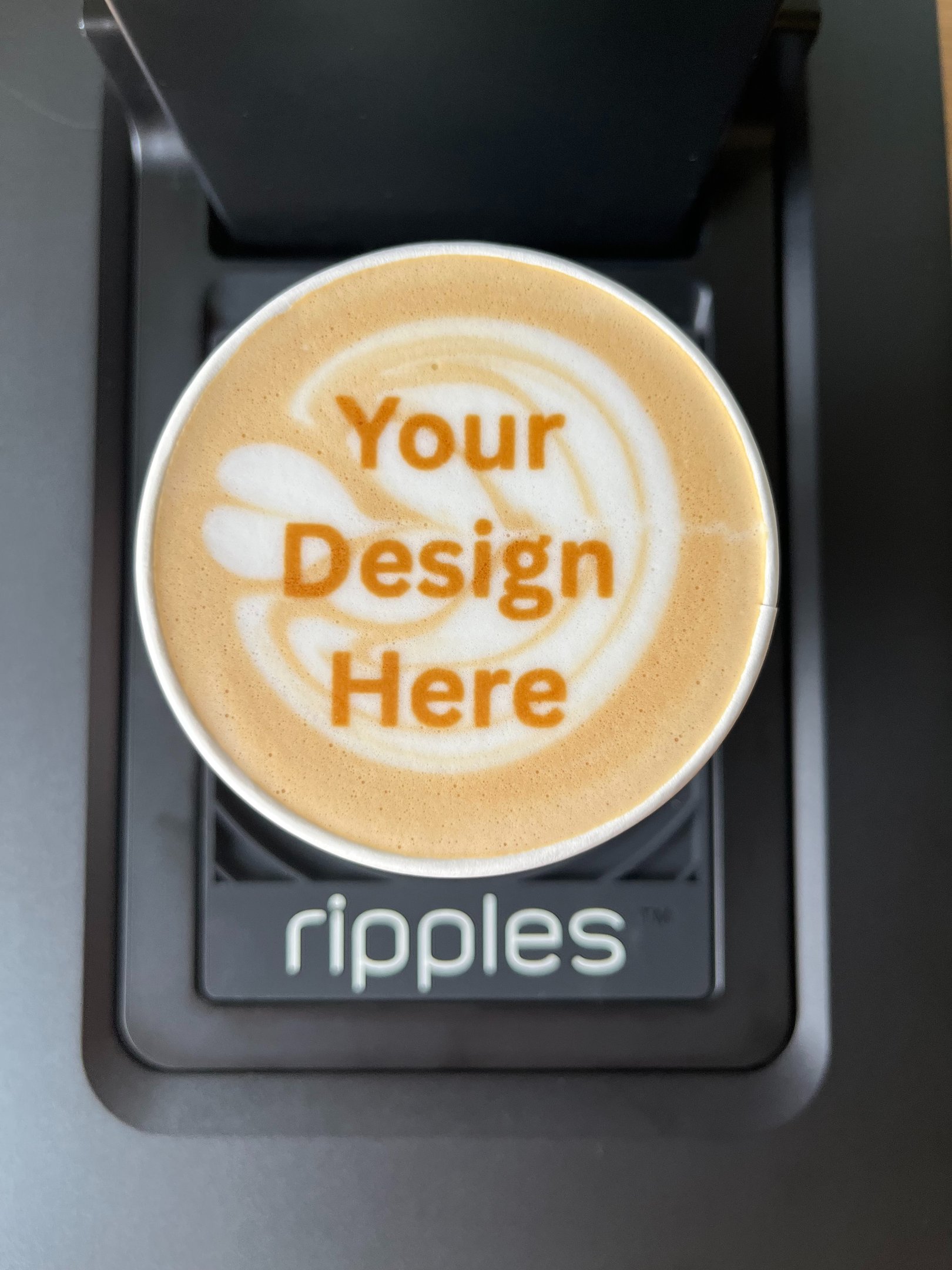 A latte with "your design here" on top of the latte art