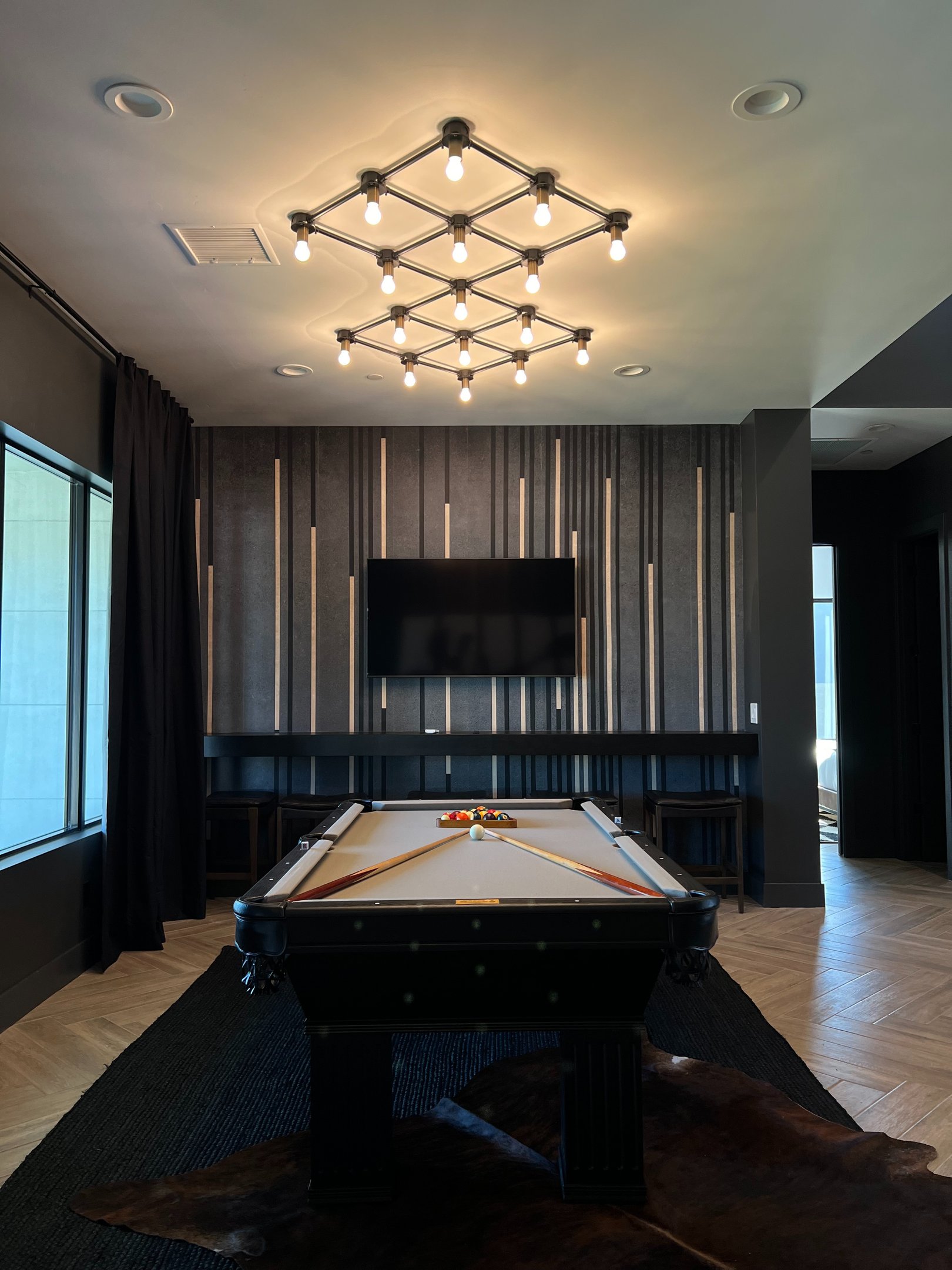 Modern accent wall featuring black, gold, and gray vertical wood slats against gray limewash