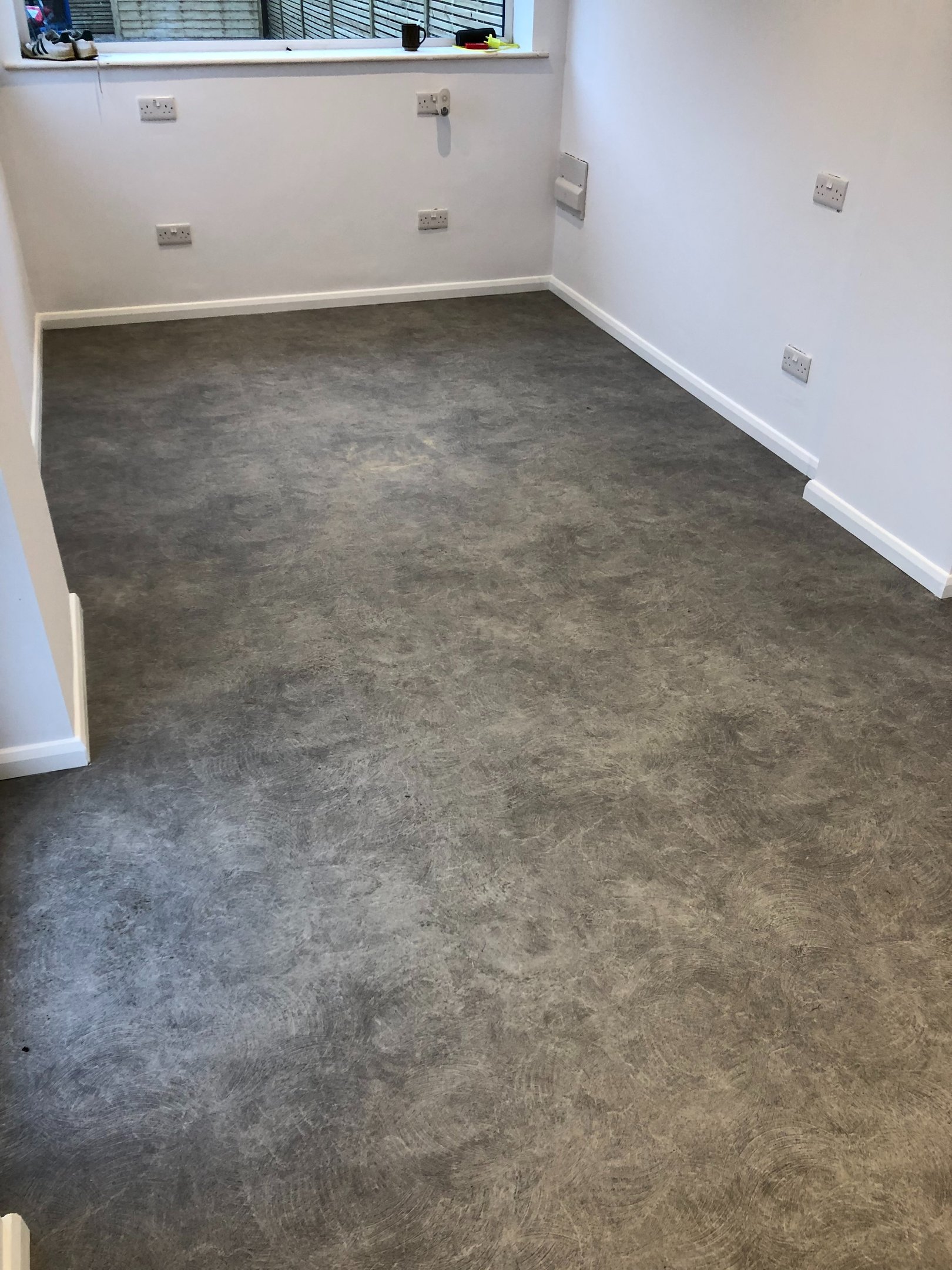 Portslade room featuring dark grey concrete effect luxury vinyl tile flooring and white walls.