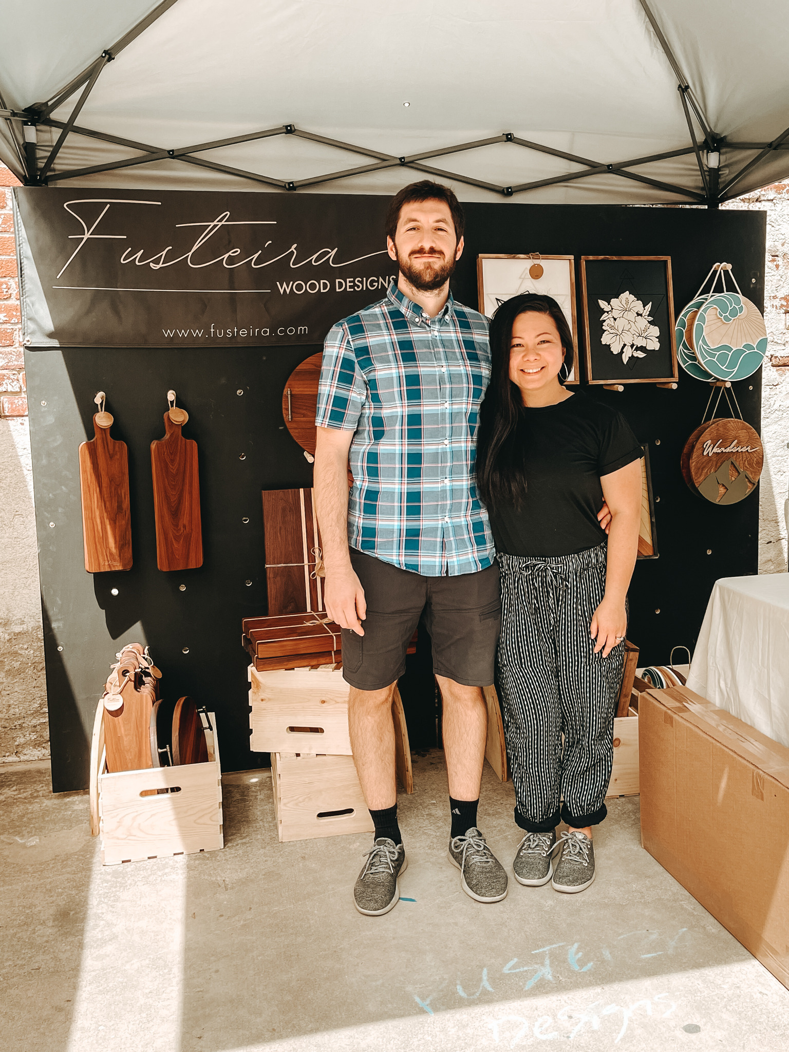 Gilliane and Victor, from Fusteira, at their booth, showcasing custom handcrafted wooden pieces.