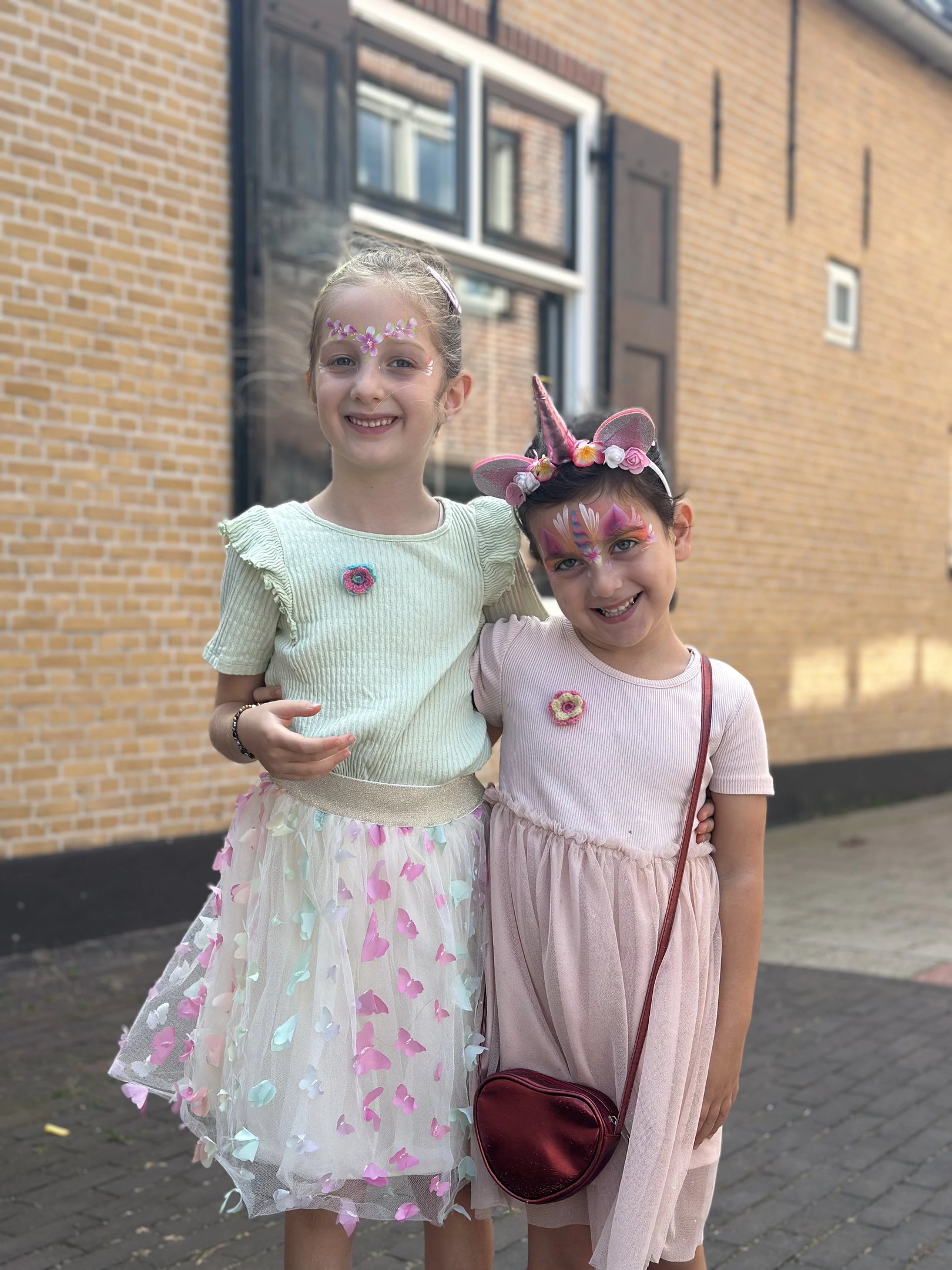 Meisje met roze en paarse eenhoorn-schmink en een bloemenhaarband.