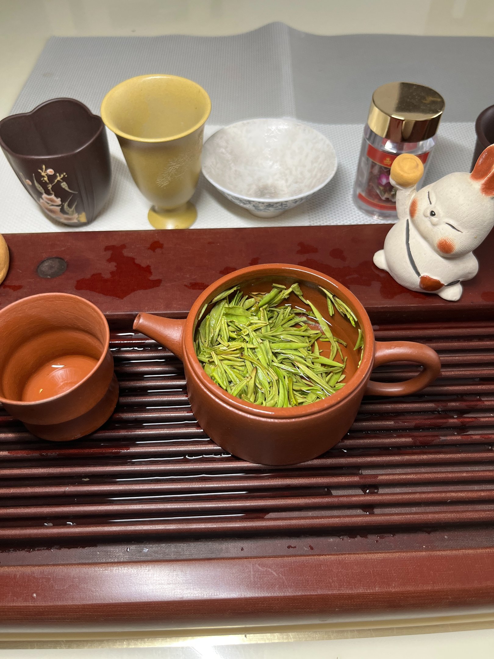 Tea set placed on a wooden tea tray, with green tea inside the teapot
