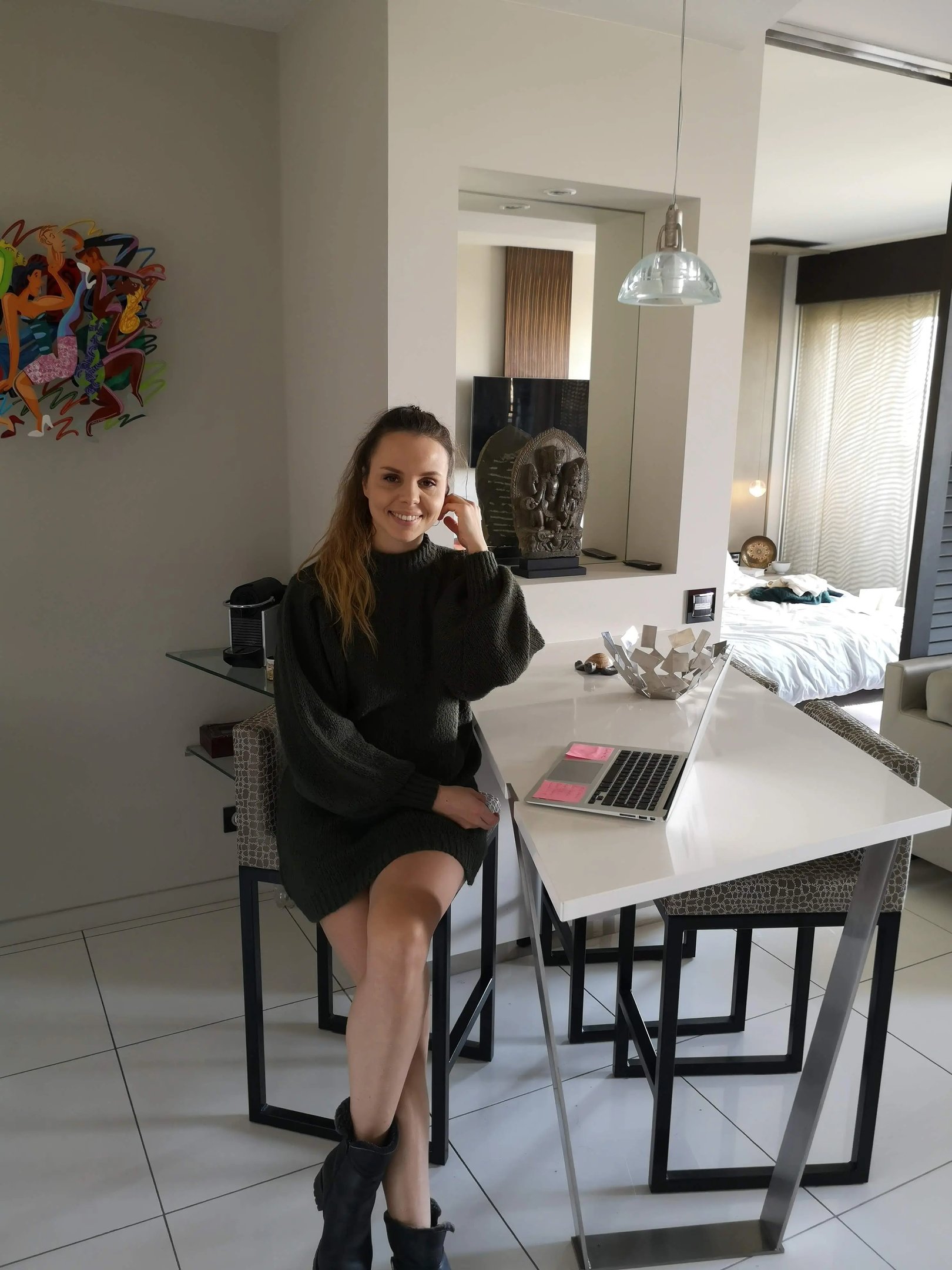 Christine Hauser, RTT Practitioner, sitting at a table with a laptop in a stylish home setting