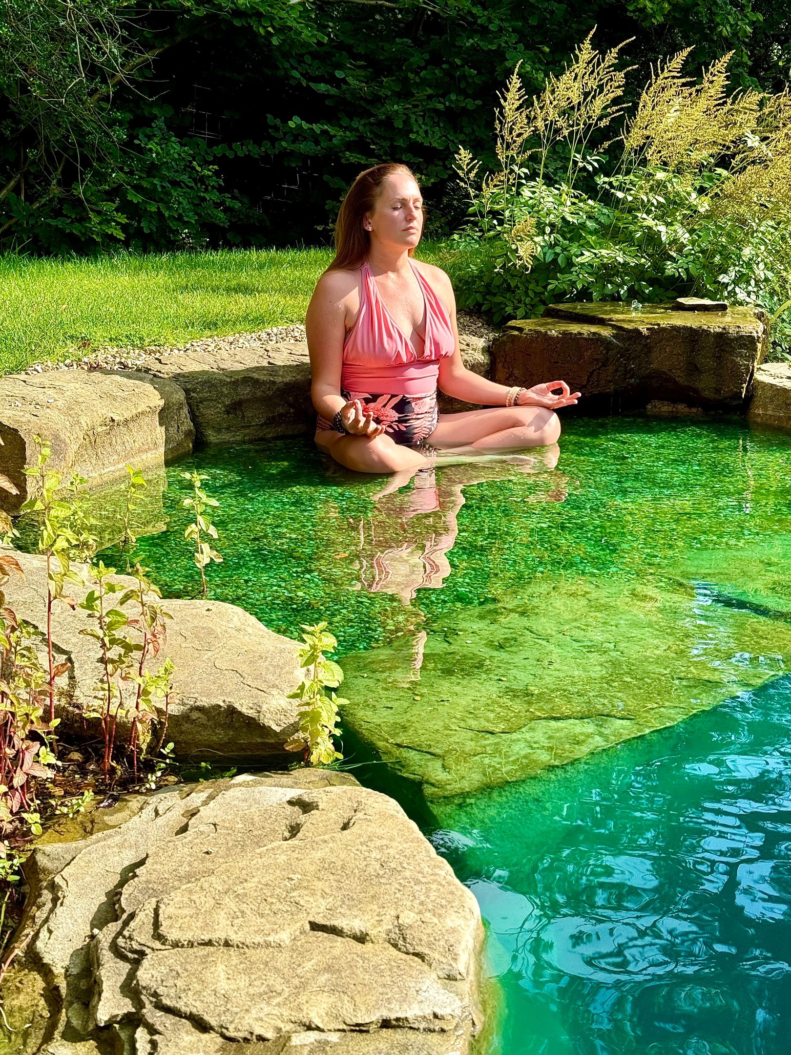 A picture of Alena Booth meditating in a natural lake in UK