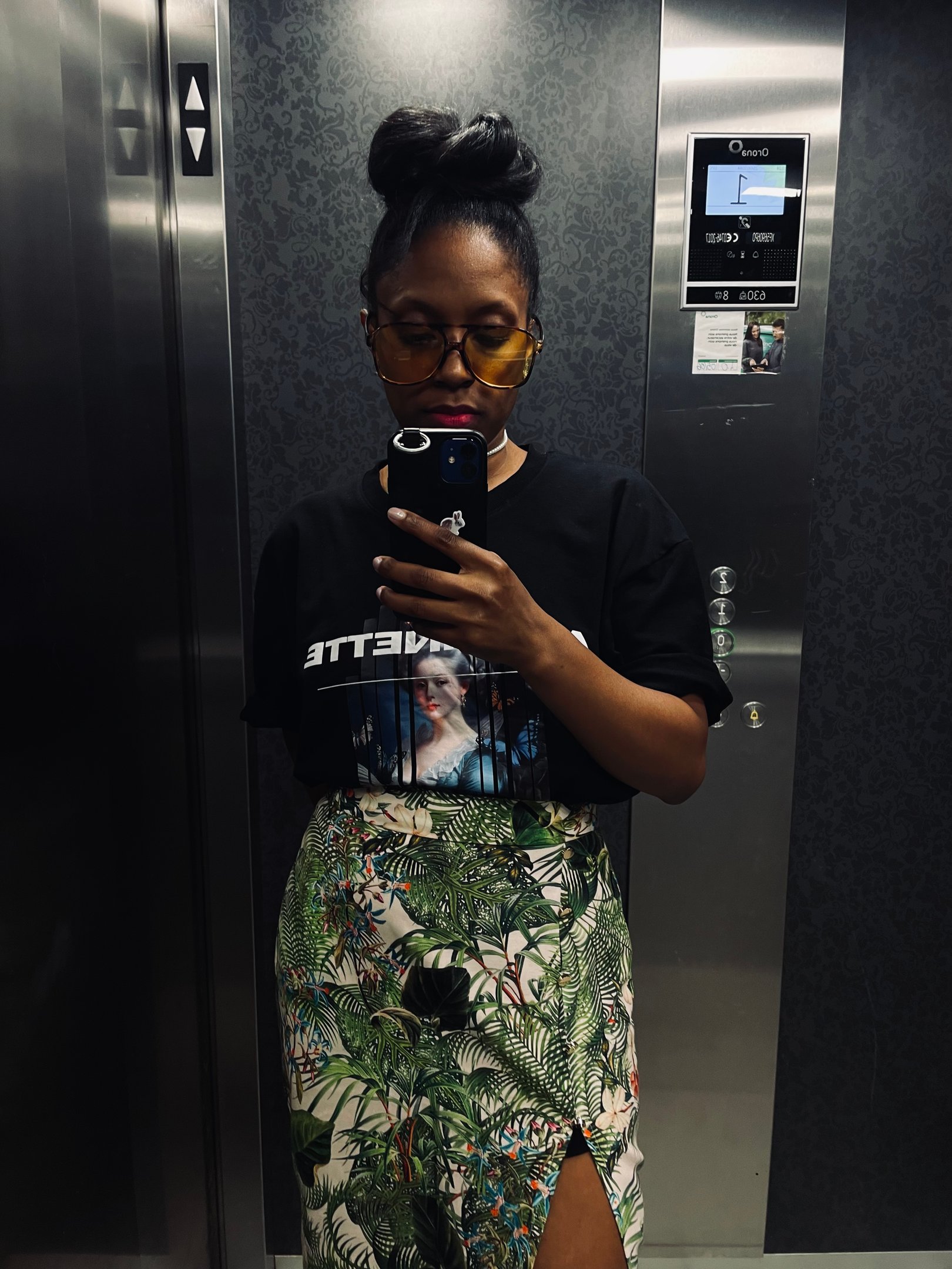 a woman in a black shirt and skirt with a phone