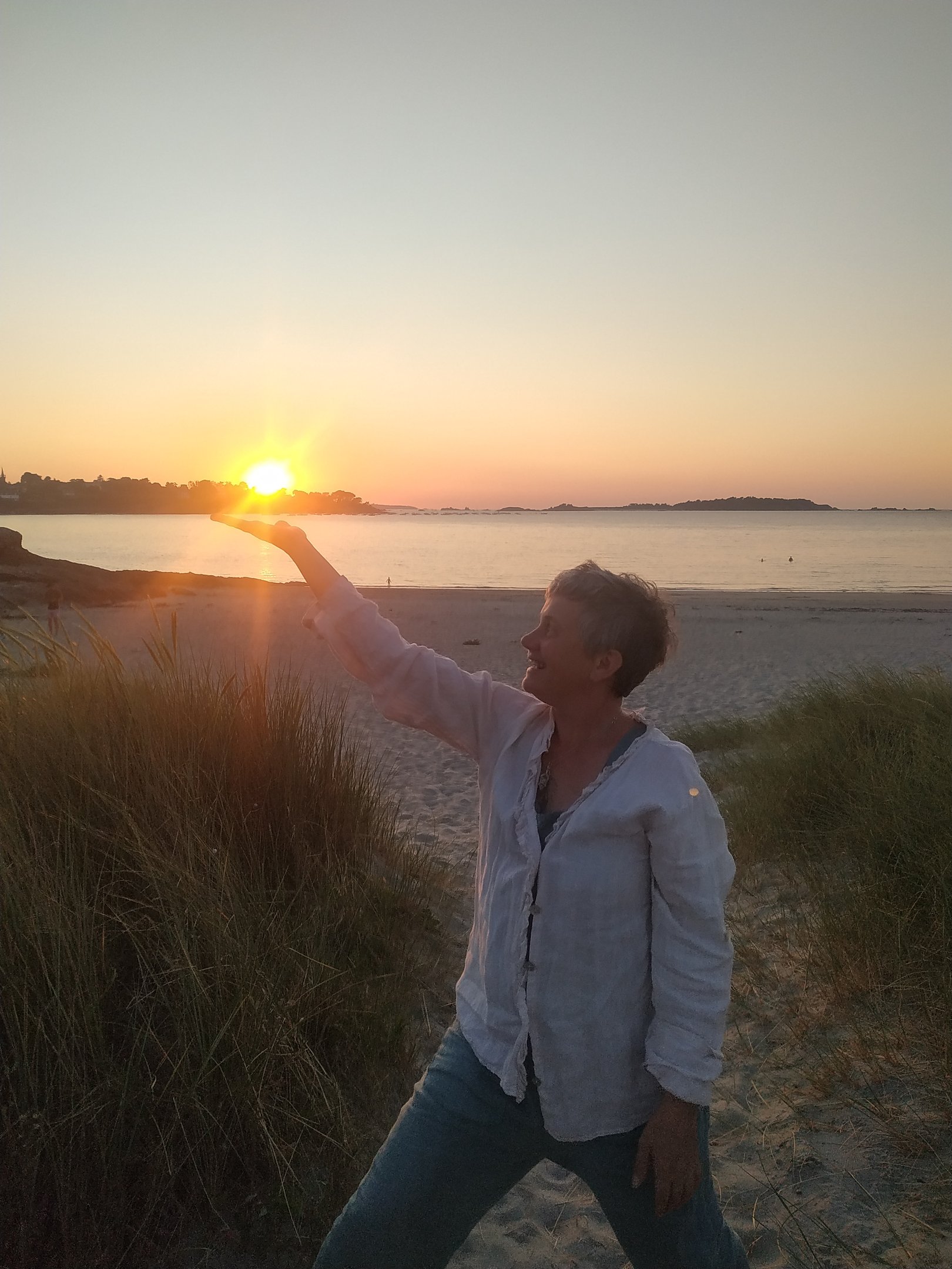 a woman is standing on a beach with her arms outstretched out to the sun