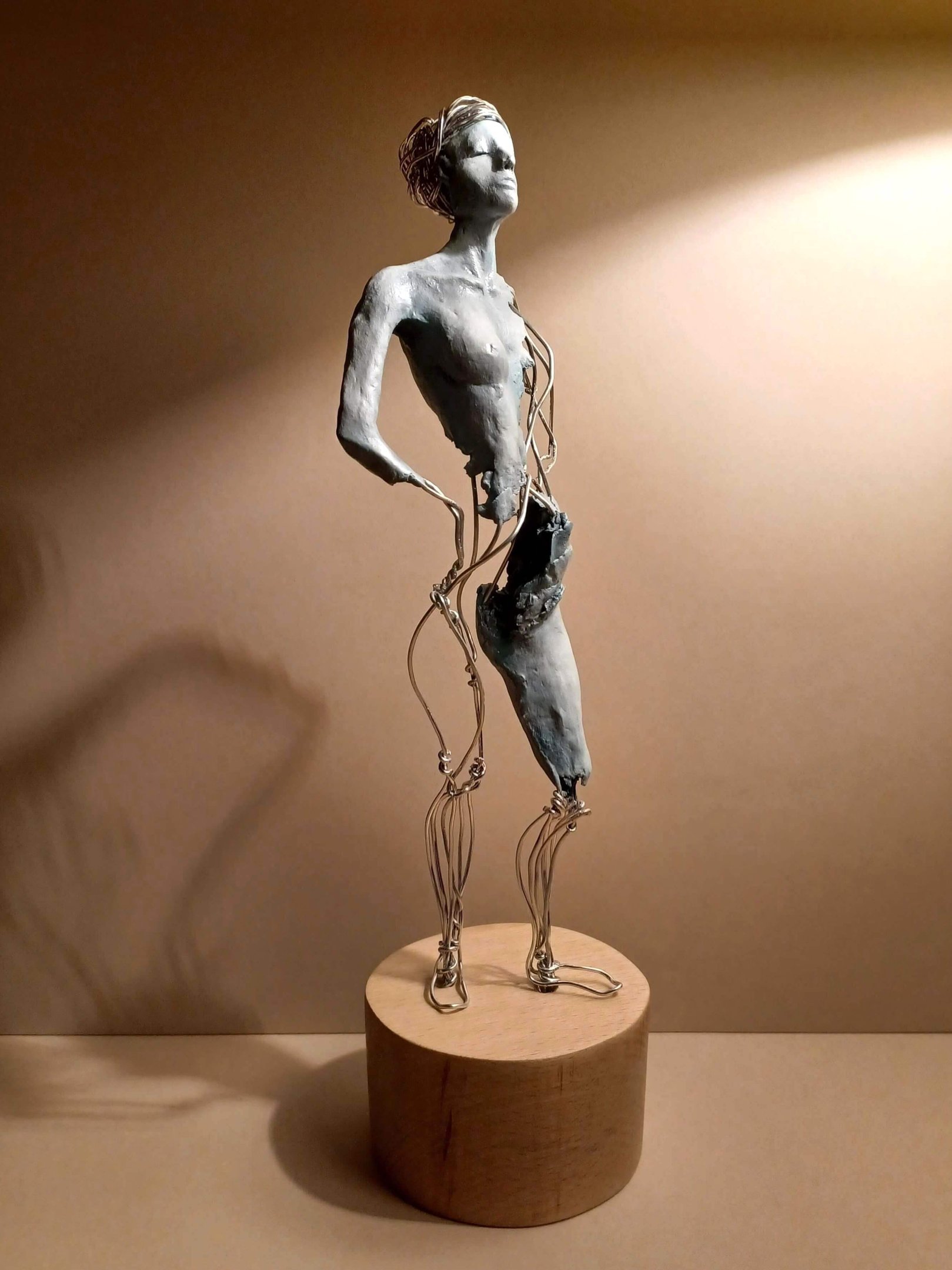 A complete sculpture of a standing female figure, part clay, part wire, hands on hips
