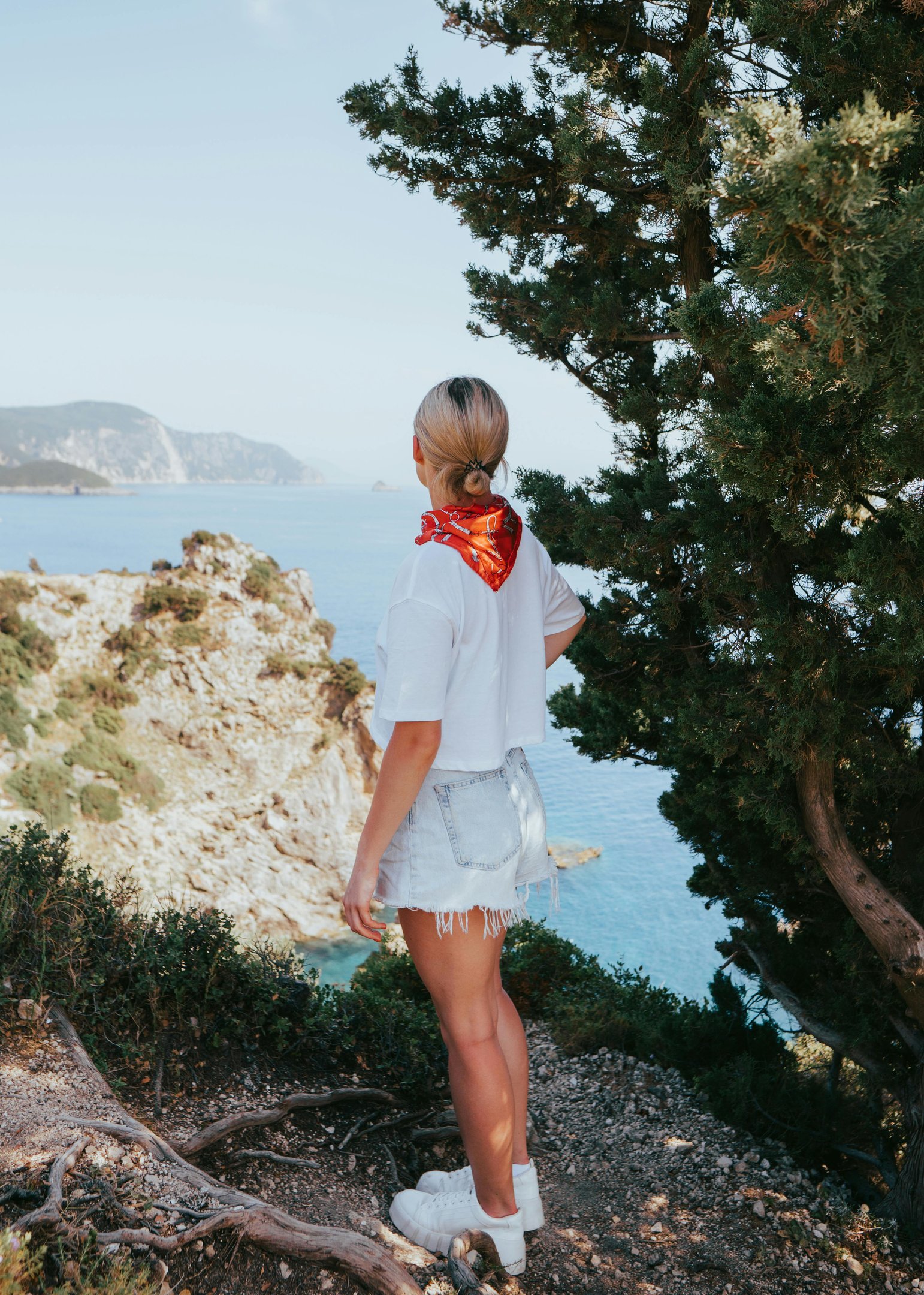 a woman standing on a hill overlooking the ocean
