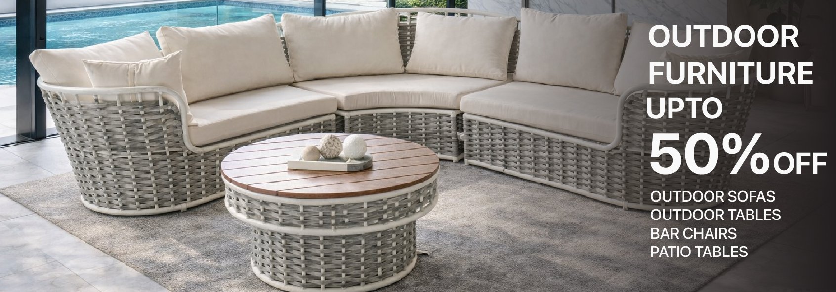 Modern woven wicker outdoor sectional sofa and round wood coffee table on a patio by a pool.