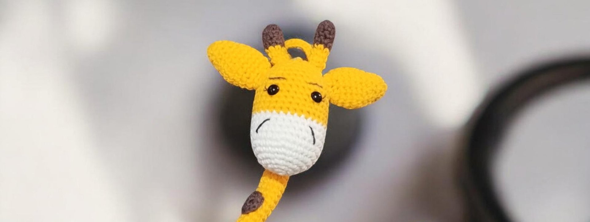 Jirafa de juguete hecha a mano con ganchillo, con detalles de hilo amarillo y blanco.