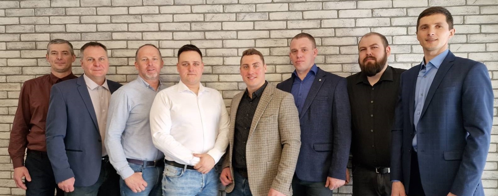 a group of men standing in front of a brick wall